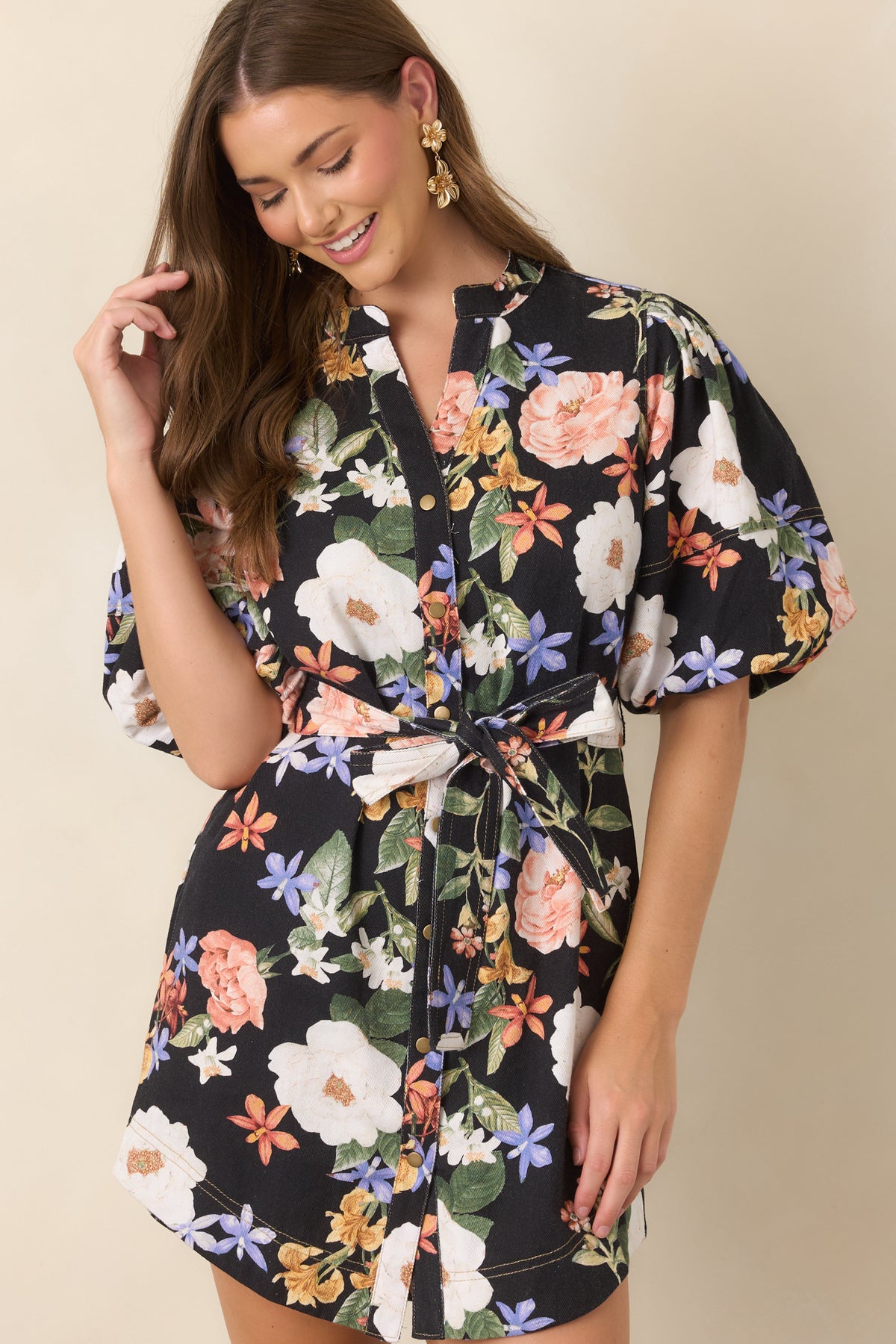 Floral black dress showcasing leafy green accents, gold-tone neckline buttons, and voluminous elbow-length sleeves.