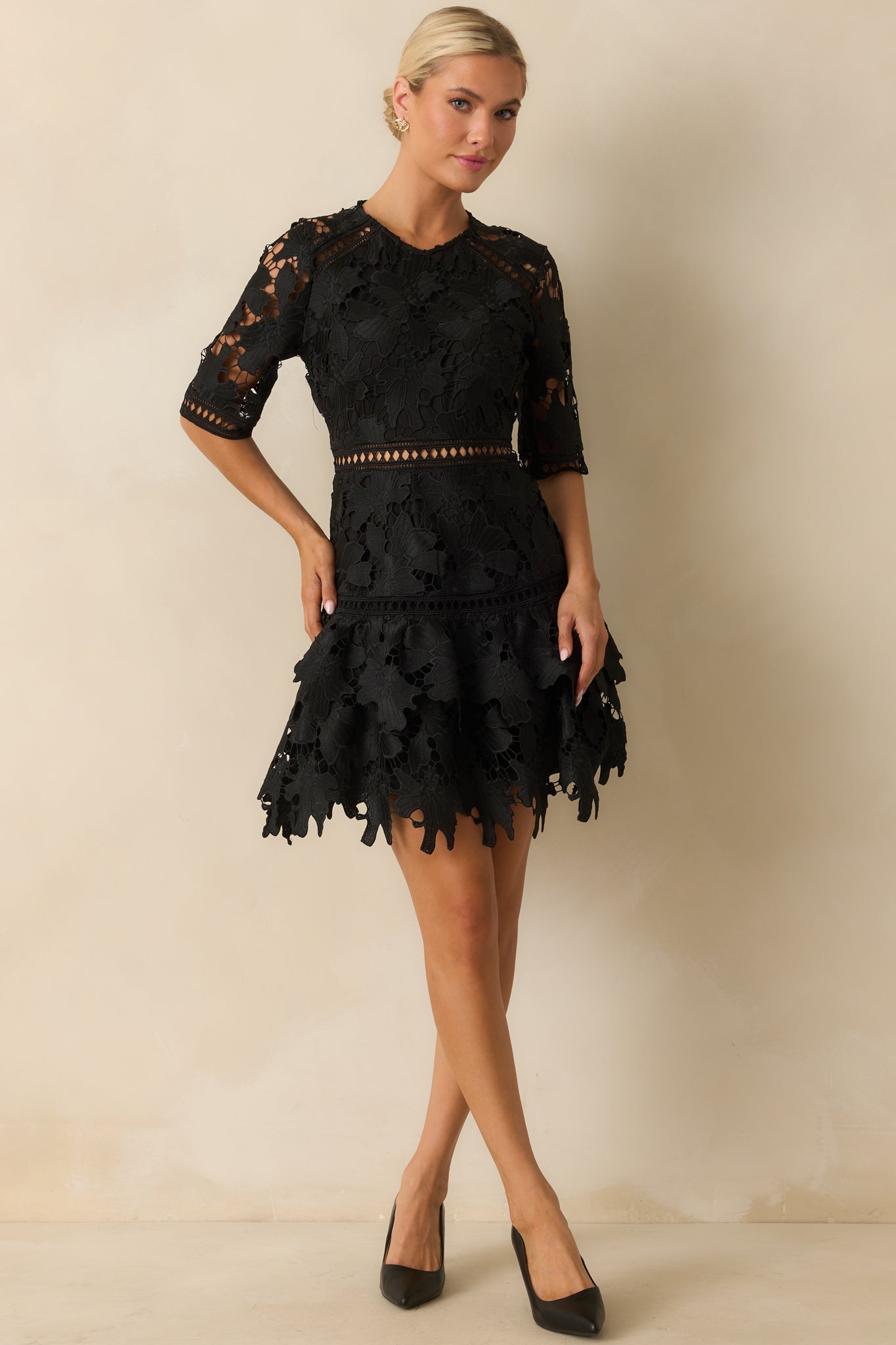 Black floral guipure lace mini dress with a round neckline and half sleeves edged in scallops.