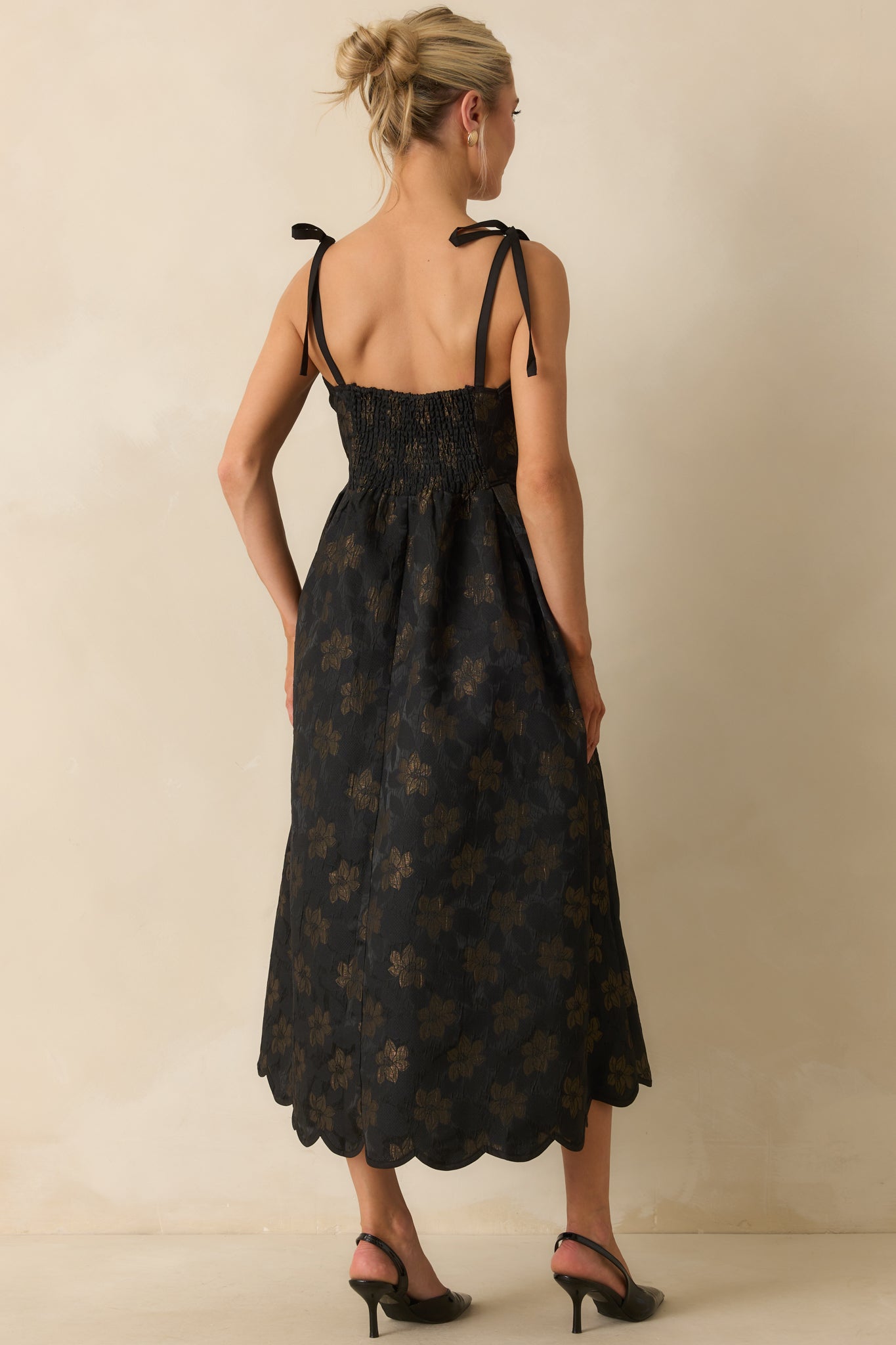 Rear view of black floral jacquard midi dress showing the smocked back panel and self-tie shoulder straps.