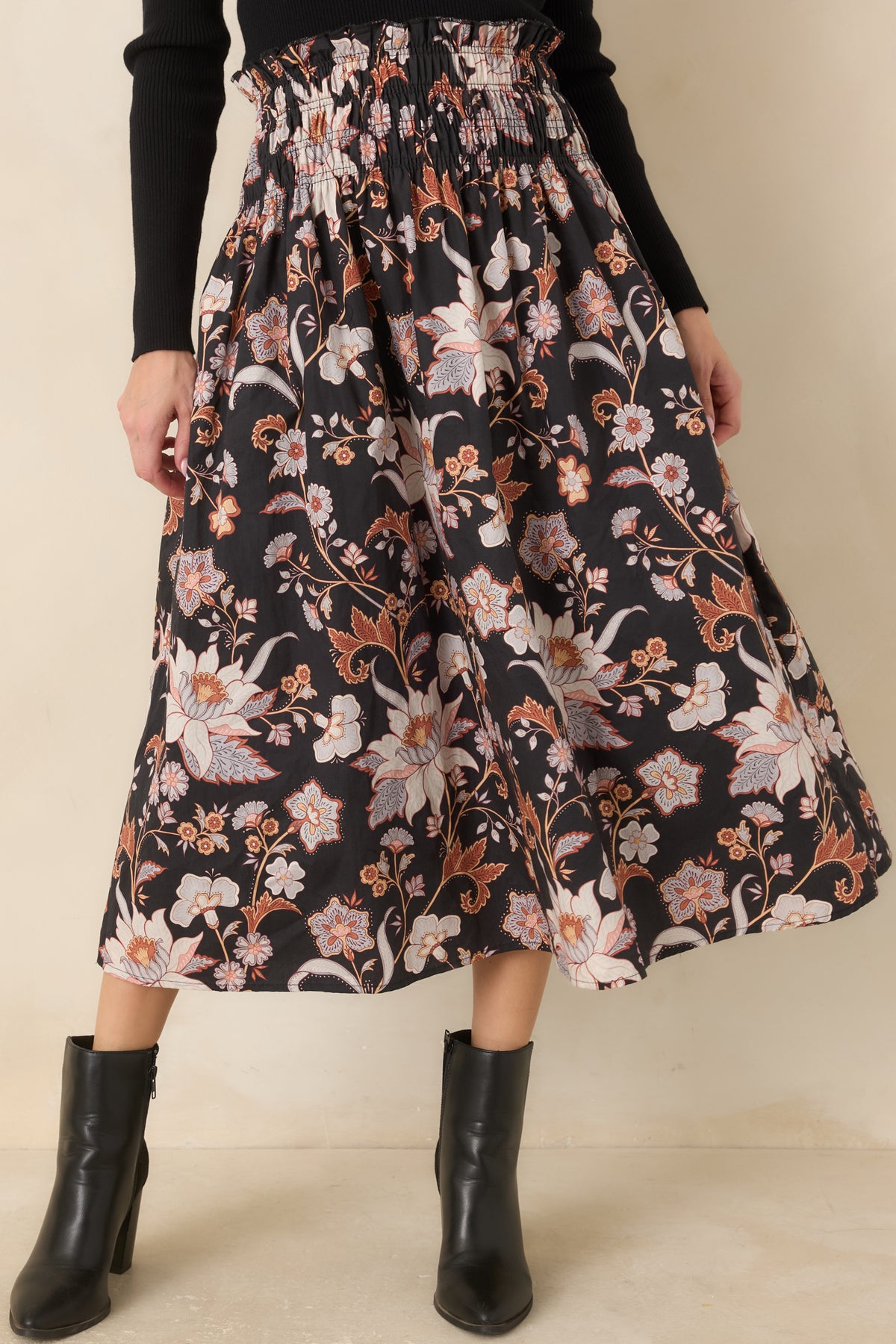 The black floral skirt features a wide smocked waistband finished with a delicate ruffled edge.