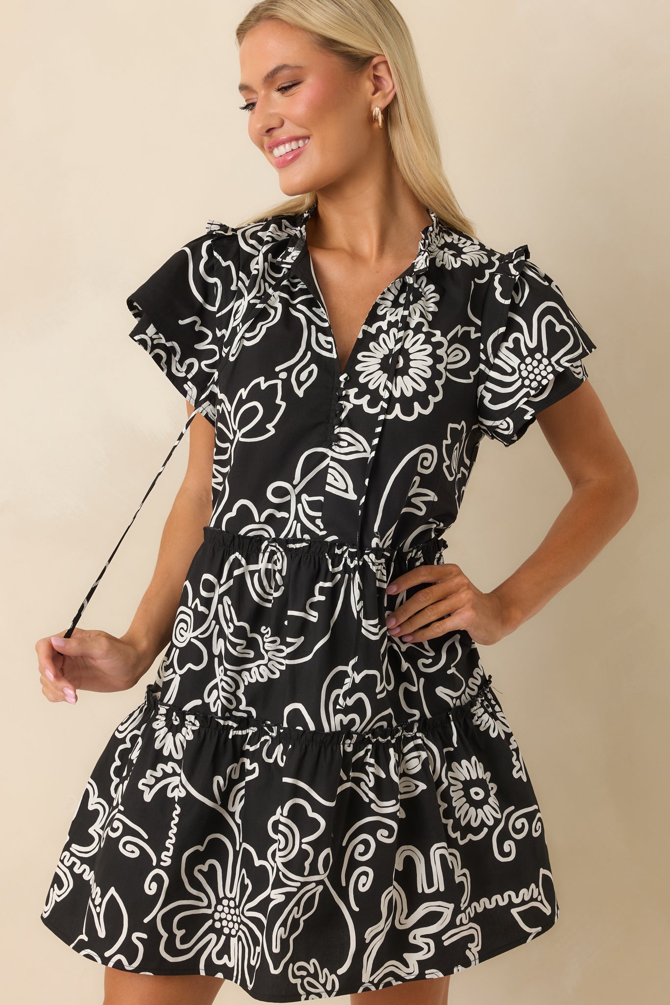 A cropped image focusing on the neckline area, showcasing the optional self-tie tassels and floral pattern.