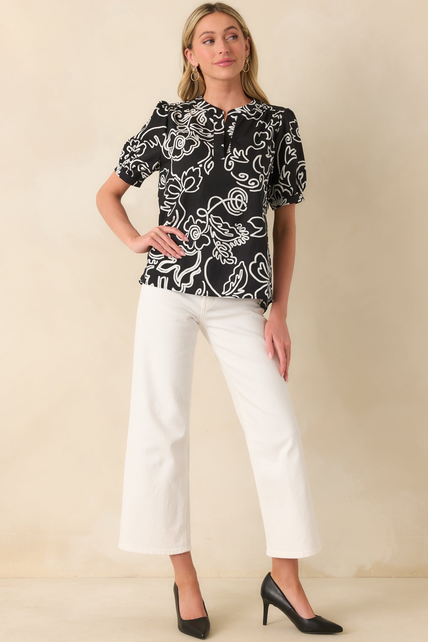 A full front view of the black top showing its white floral print, notch v-neckline, and relaxed fit silhouette.