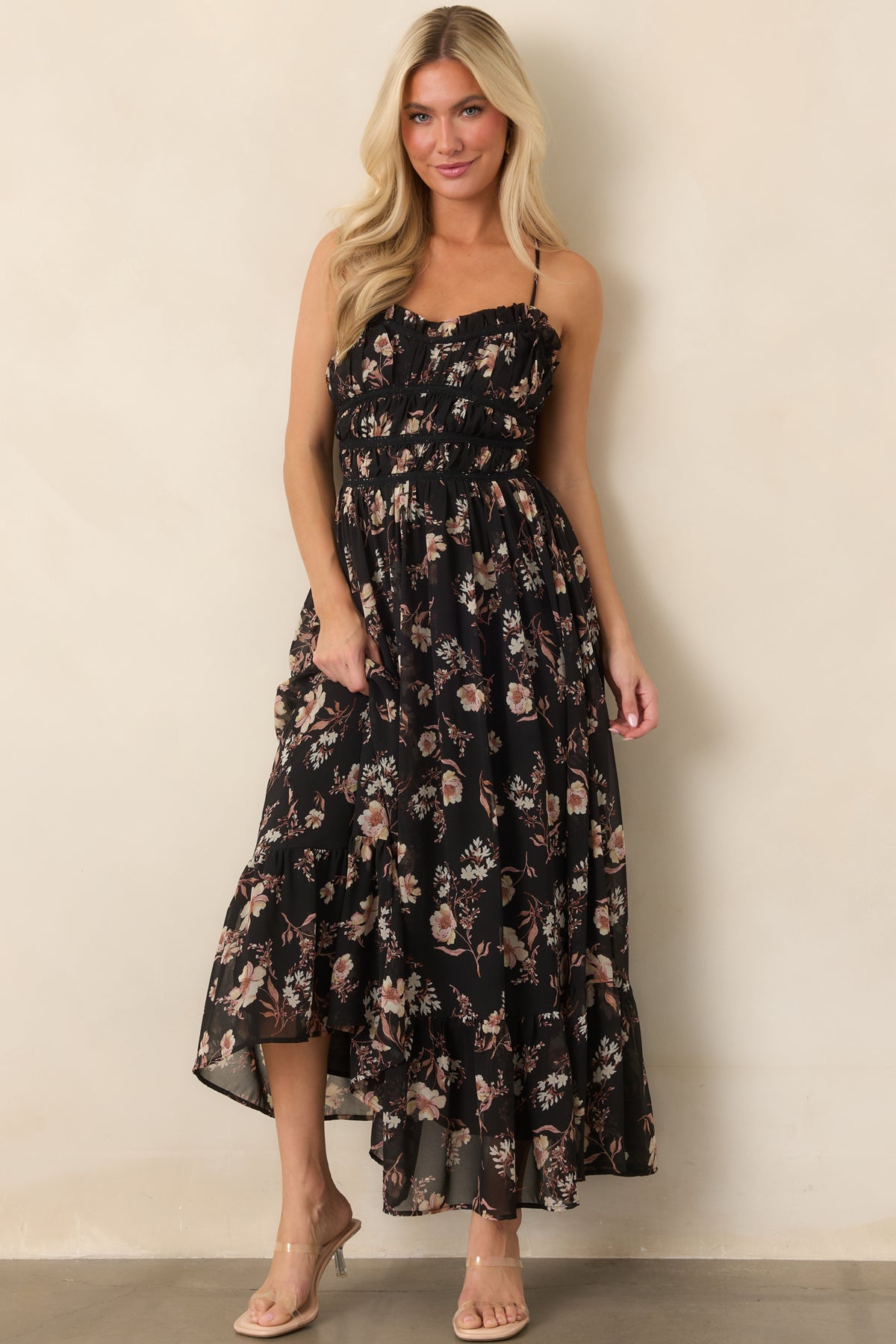 Black floral dress featuring a sheer outer layer, delicate horizontal bodice trim, ruffled neckline, and softly flowing hem.