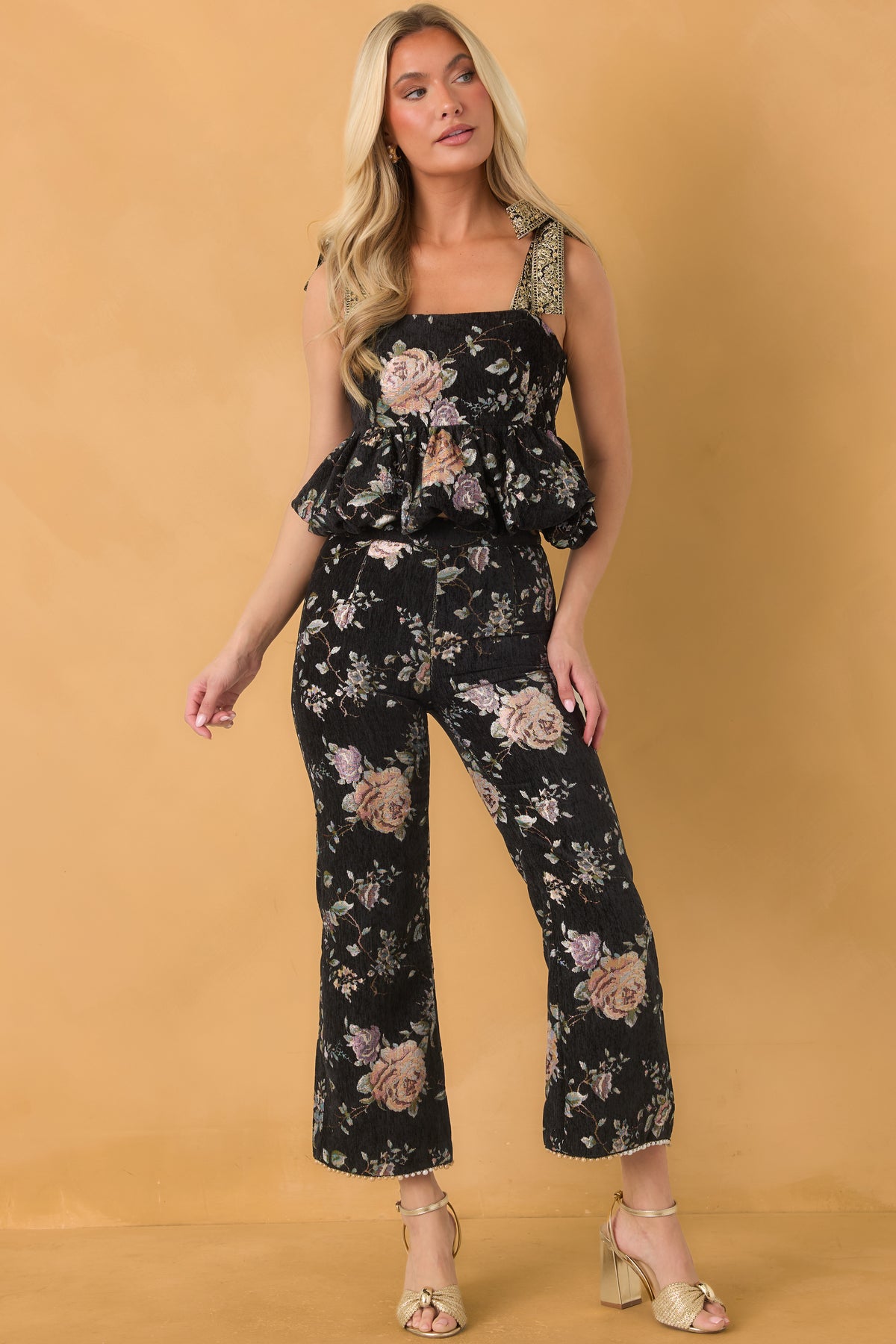 Black cropped top with muted pink, peach, lavender, and green floral tapestry detailing and a gathered bubble hem.