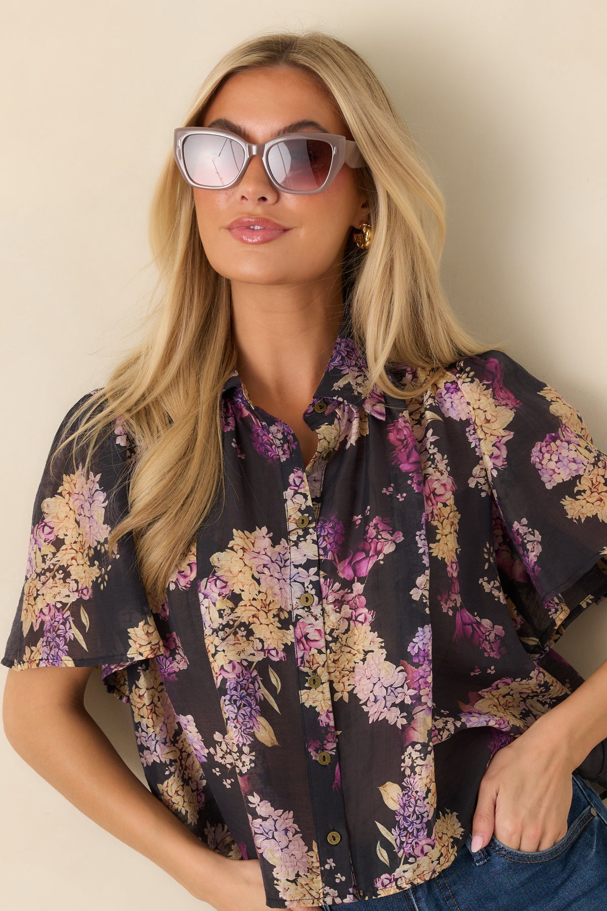 Slightly cropped hem finishes the loose black floral top with a softly draped silhouette.