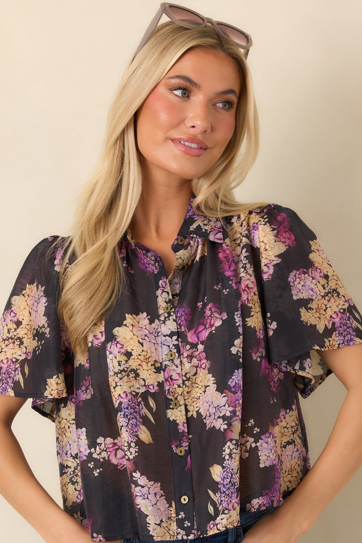 Pointed collar and button-front detailing give the black floral top a classic tailored finish.