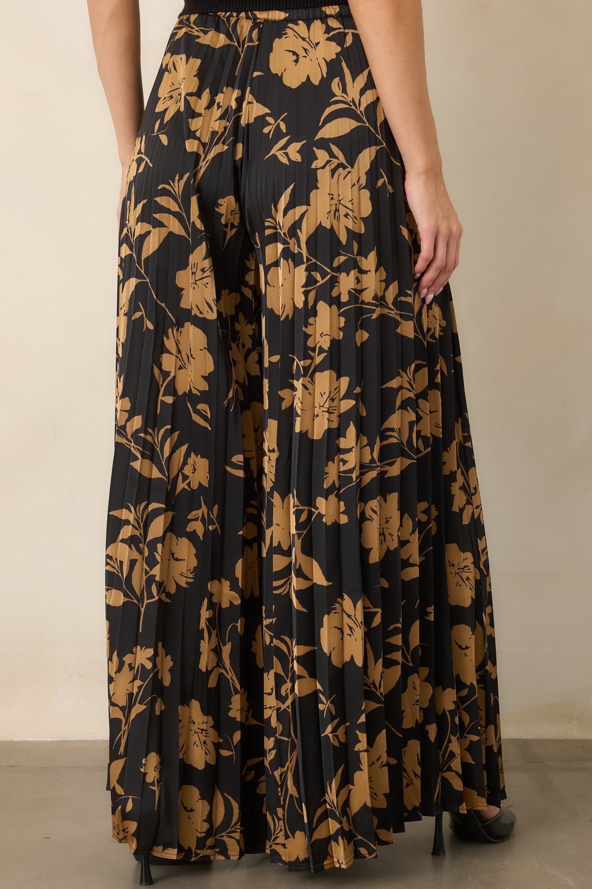 Rear of the black floral pants showing the elasticized waistband and flowing wide-leg silhouette.
