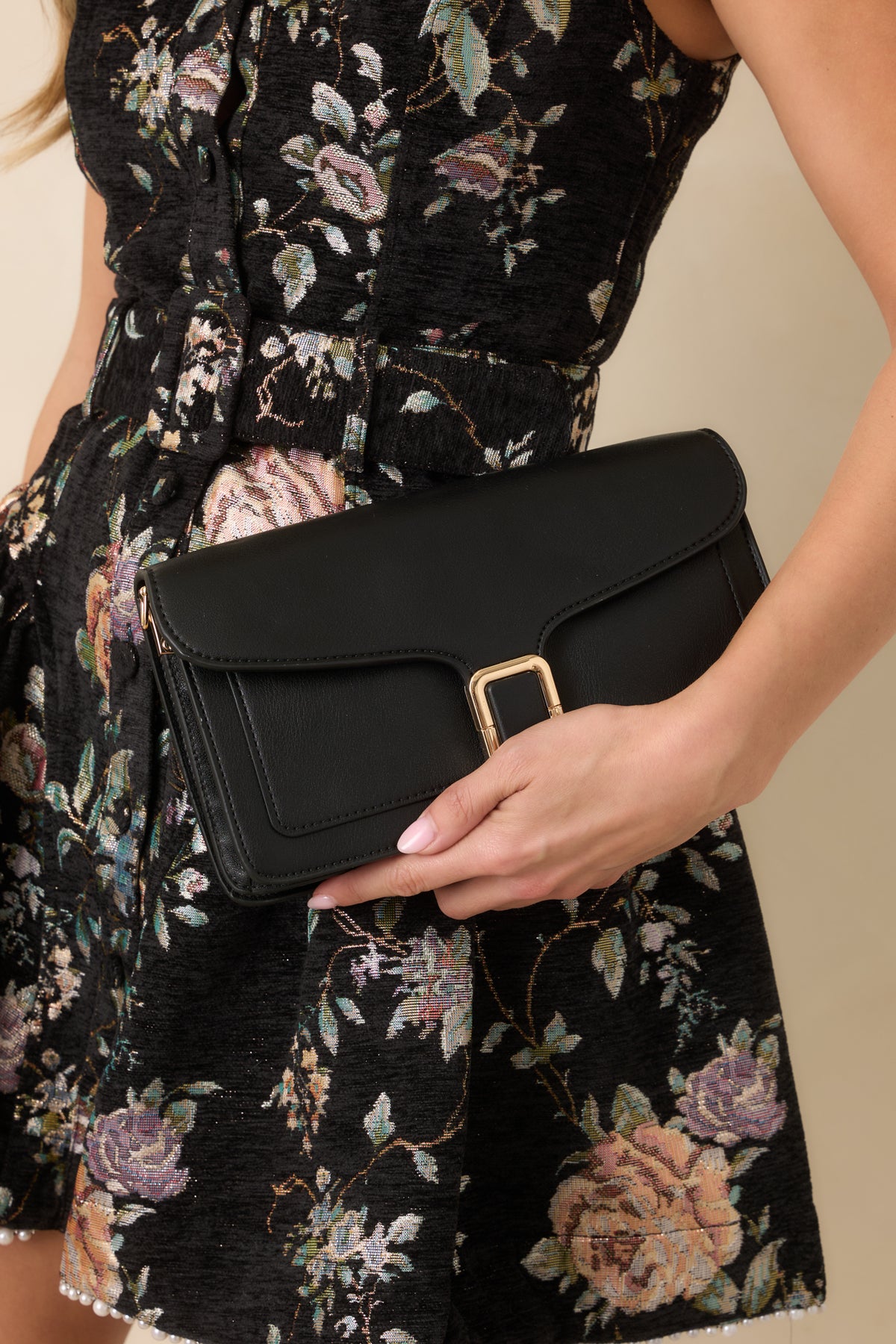 Close-up of the polished gold-tone buckle clasp and tonal edge stitching on the black faux leather handbag.