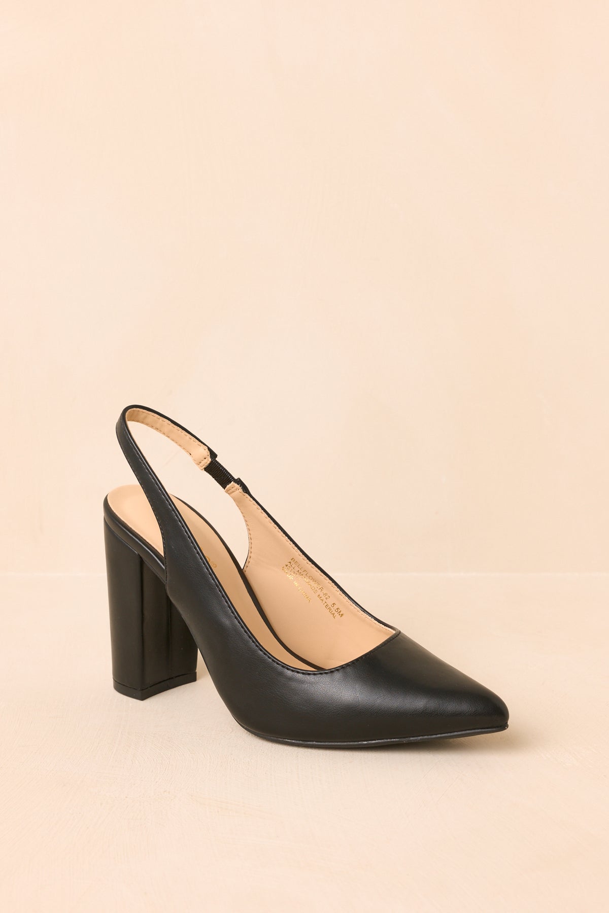 Angled view showcases the smooth black finish, pointed toe, open slingback design, and substantial block heel.