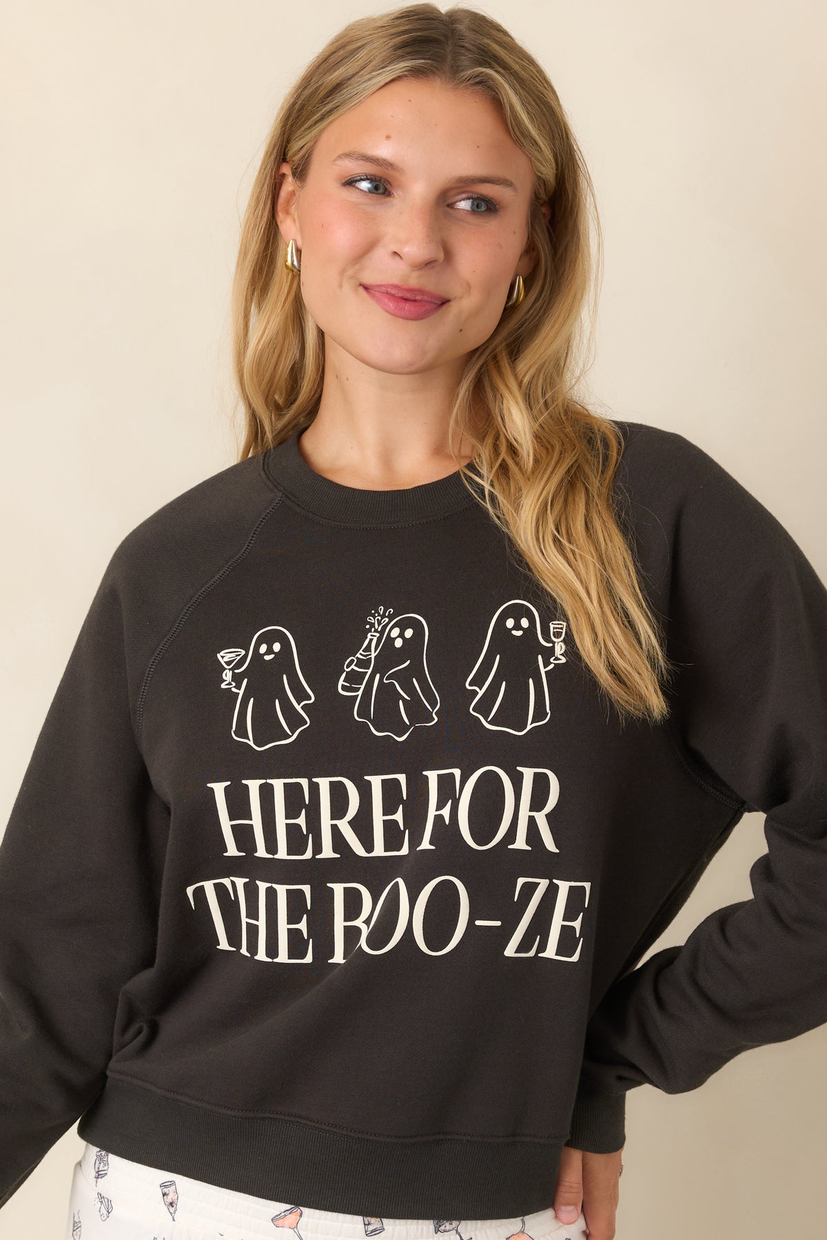 Black sweatshirt displaying oversized “Here for the Boo-ze” lettering beneath three playful ghosts carrying cocktail glasses.
