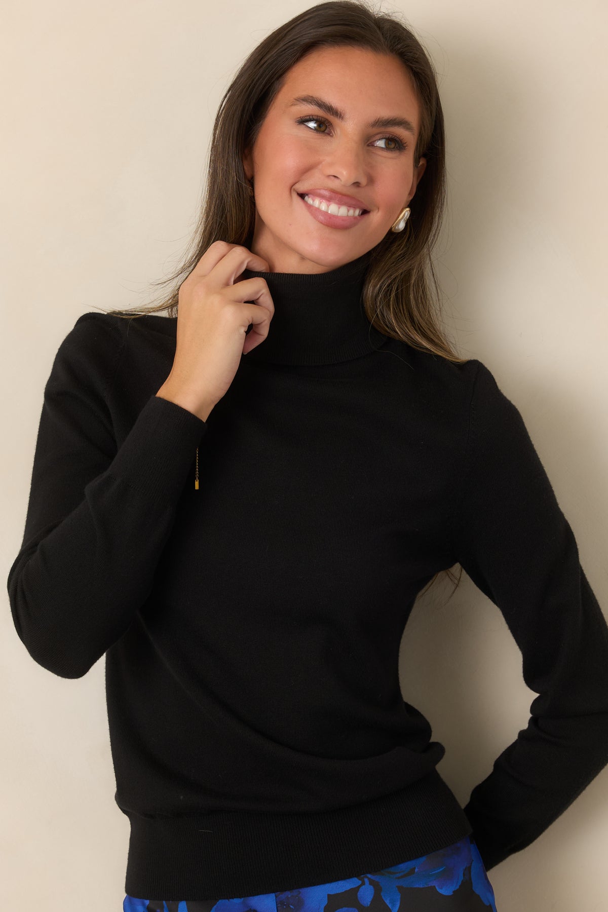 Black knit sweater showcasing long sleeves with ribbed cuffs.