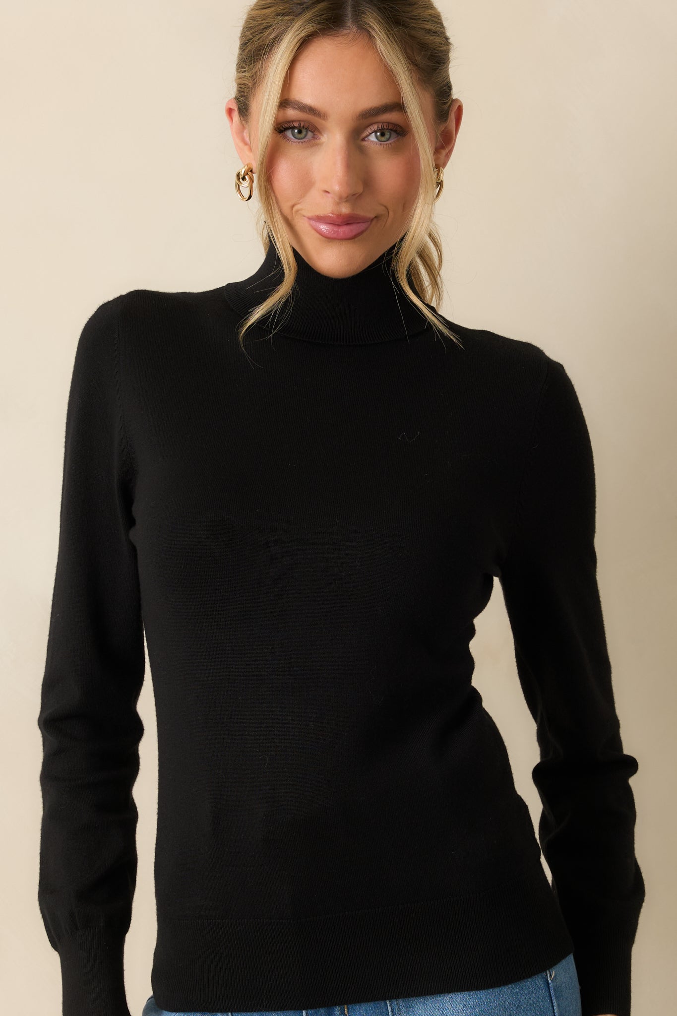 Black knit sweater displaying the turtleneck and upper chest area with a clean, minimal design.