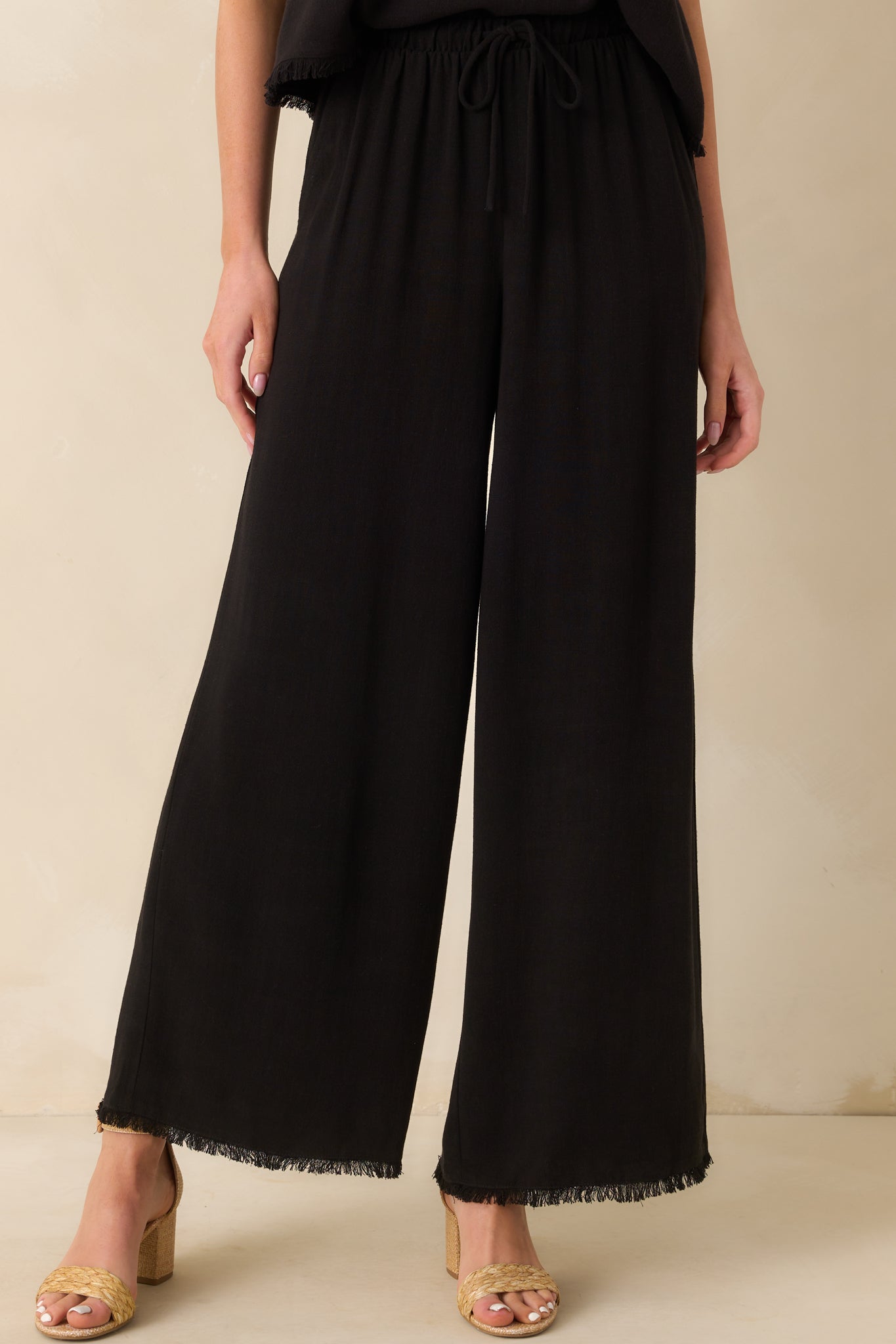 A cropped lower leg image drawing attention to the raw, frayed hem and wide leg opening.