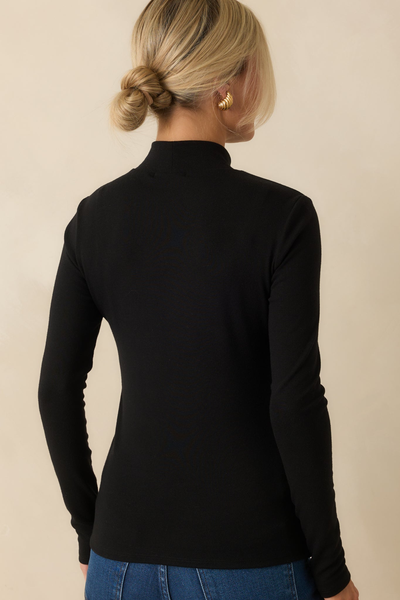Black long sleeve turtleneck top with a streamlined fit from the rear.