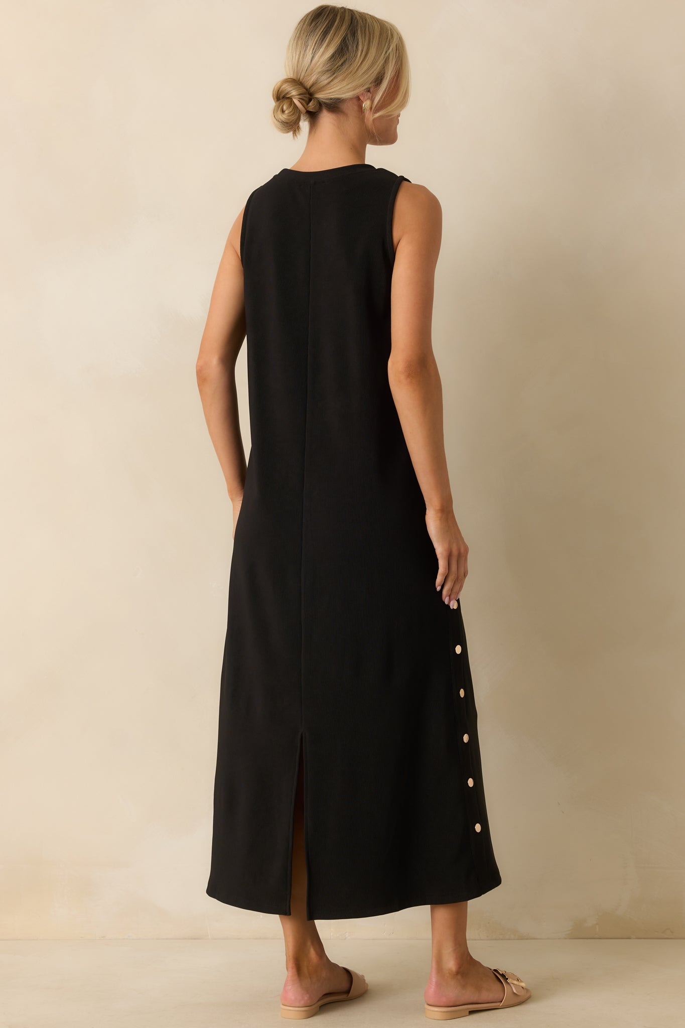 A back view of the black maxi dress showing the center seam and back vent slit.