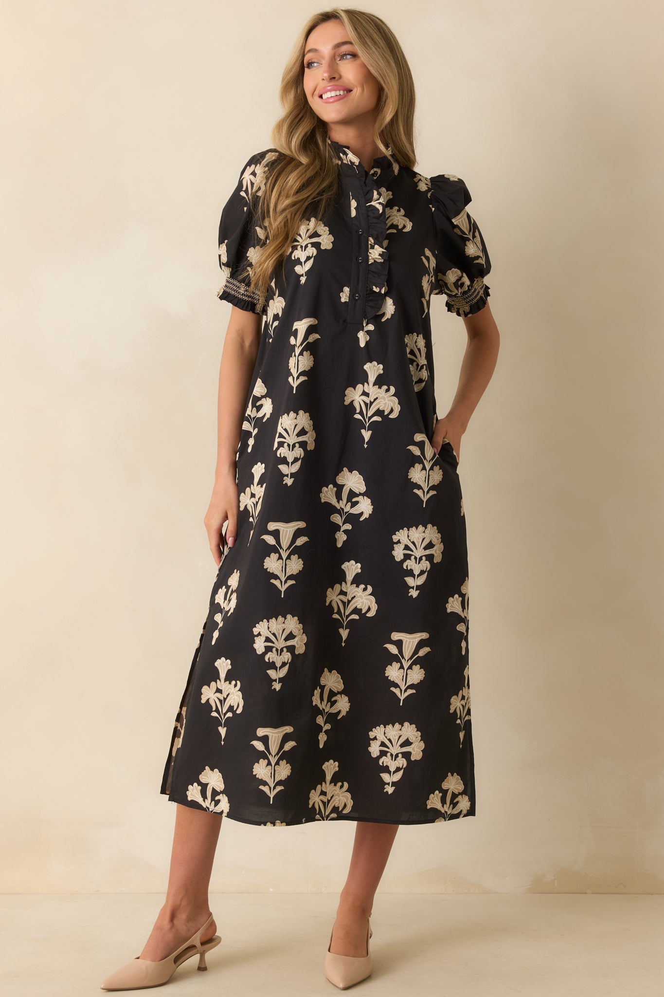 Black maxi dress with an ivory floral print, short puff sleeves with smocked cuffs, and a ruffled mock neckline.