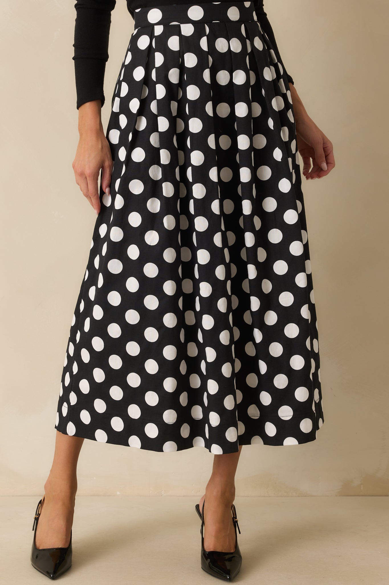 Black maxi skirt with white polka dots, high rise waist, and pleated A-line silhouette.