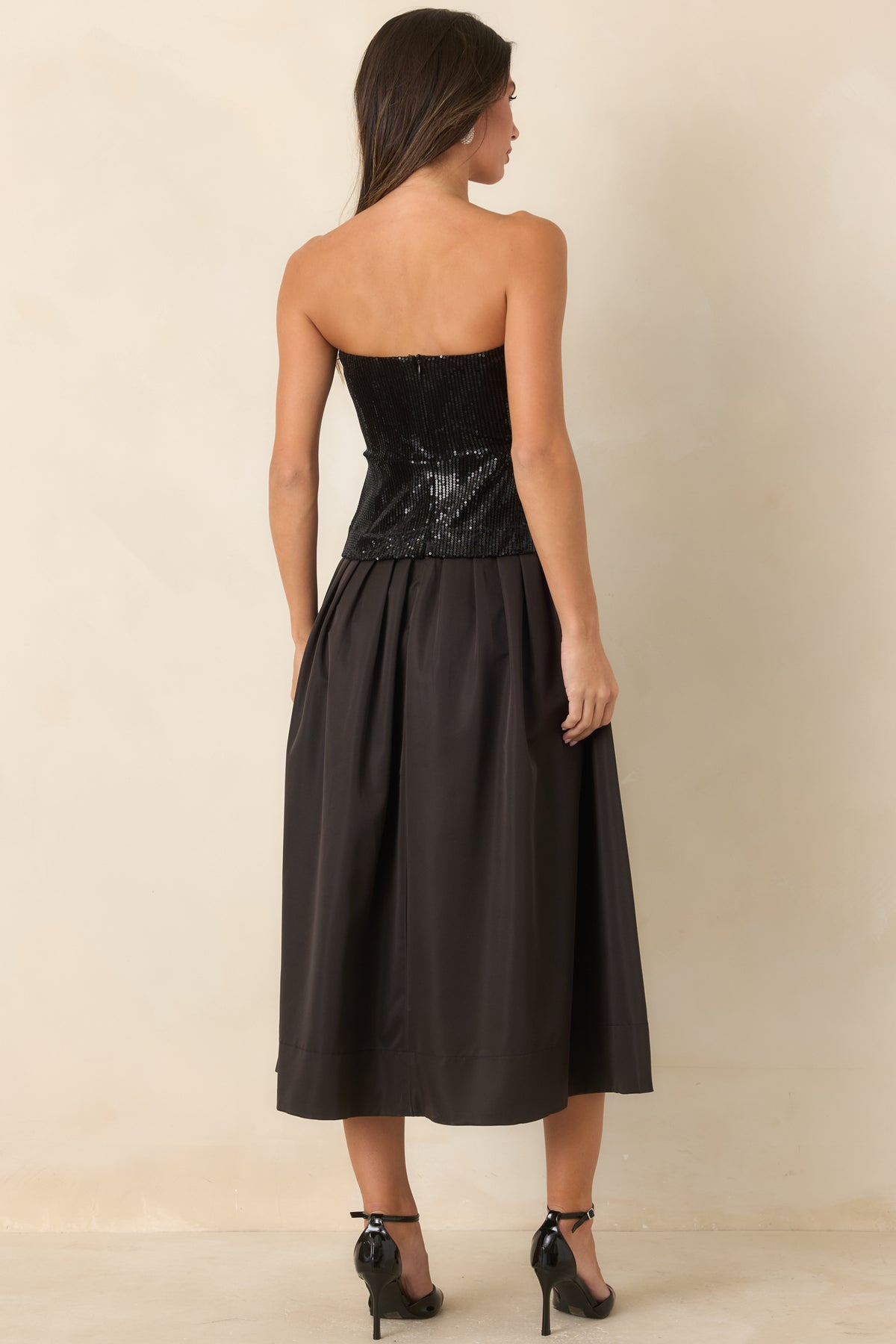 Rear of the black midi dress showing the back zipper closure and full pleated skirt.