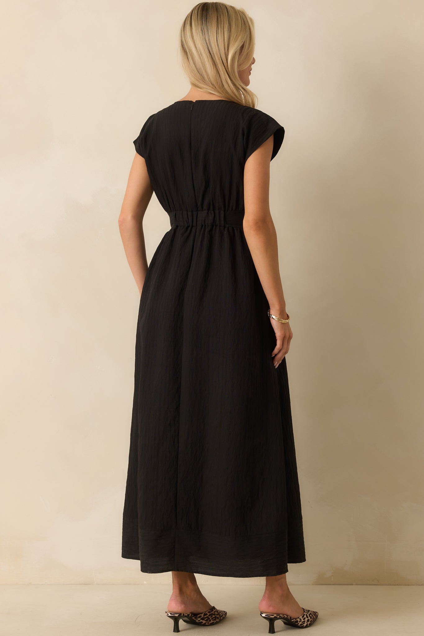 Rear view of the black midi dress showing the back elastic waistband, hidden zipper, and functional pockets.