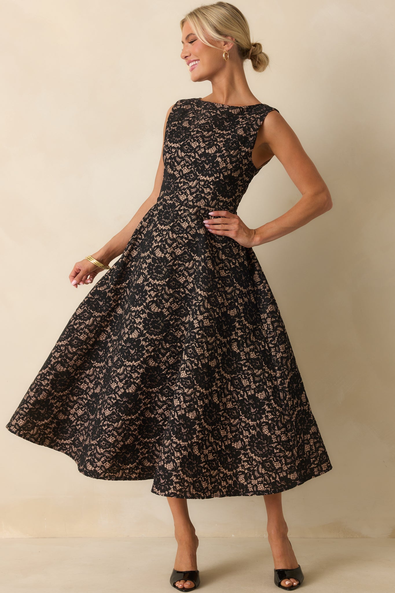 Black midi dress with floral lace overlay and tan lining, styled with a bateau neckline and sleeveless bodice.