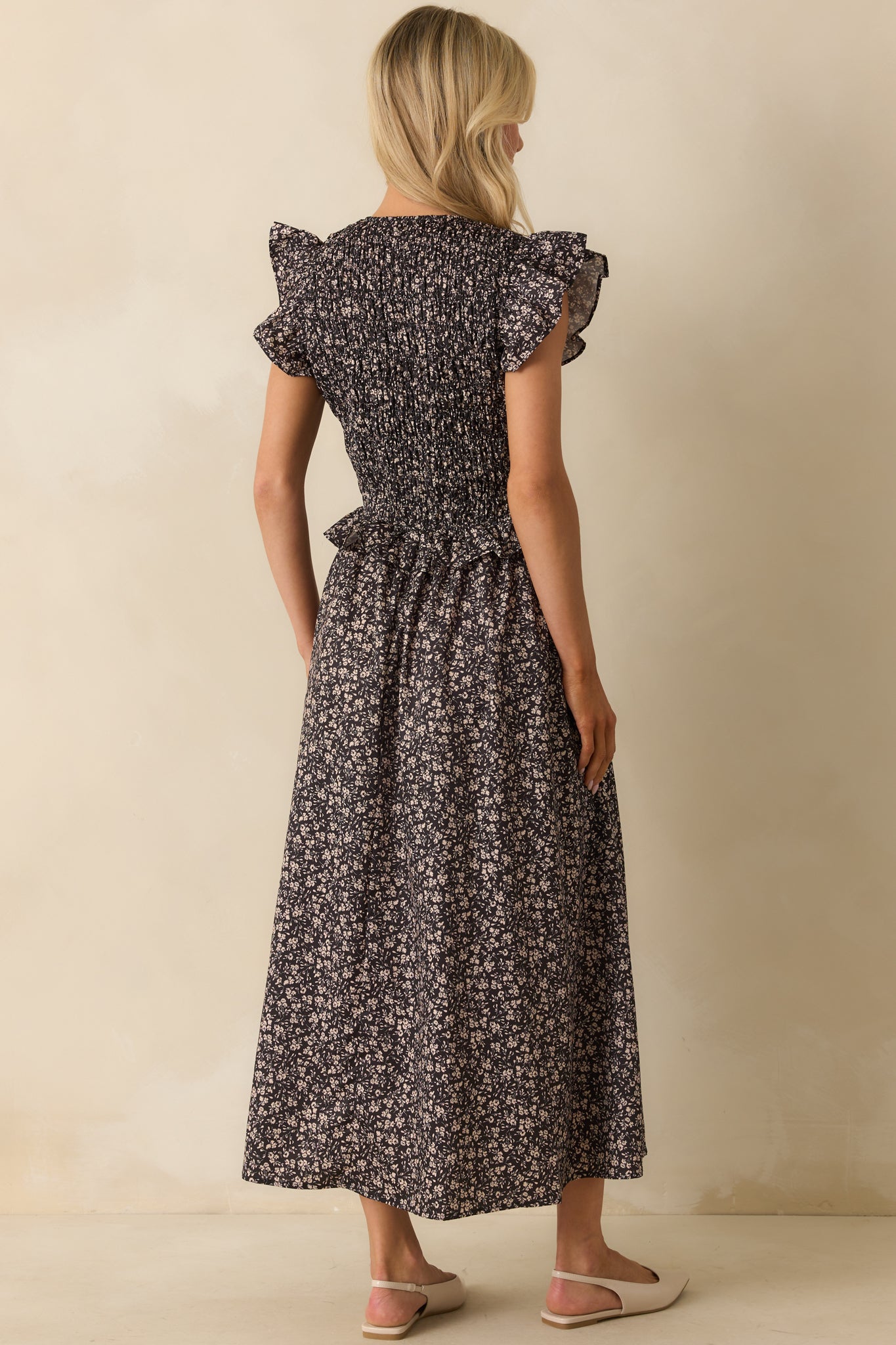 Rear view of the black midi dress showing the smocked back and flowy skirt.