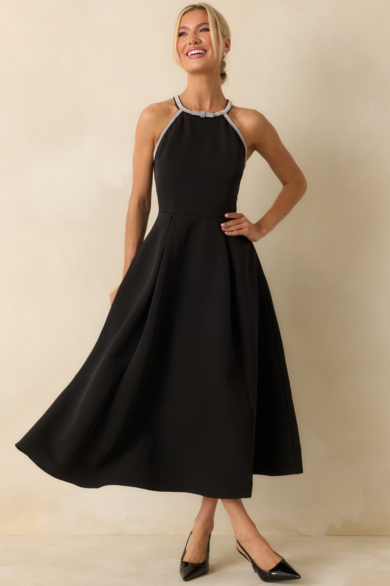 Sophisticated black midi dress showcasing a rhinestone-accented halter neckline and structured pleated A-line shape.