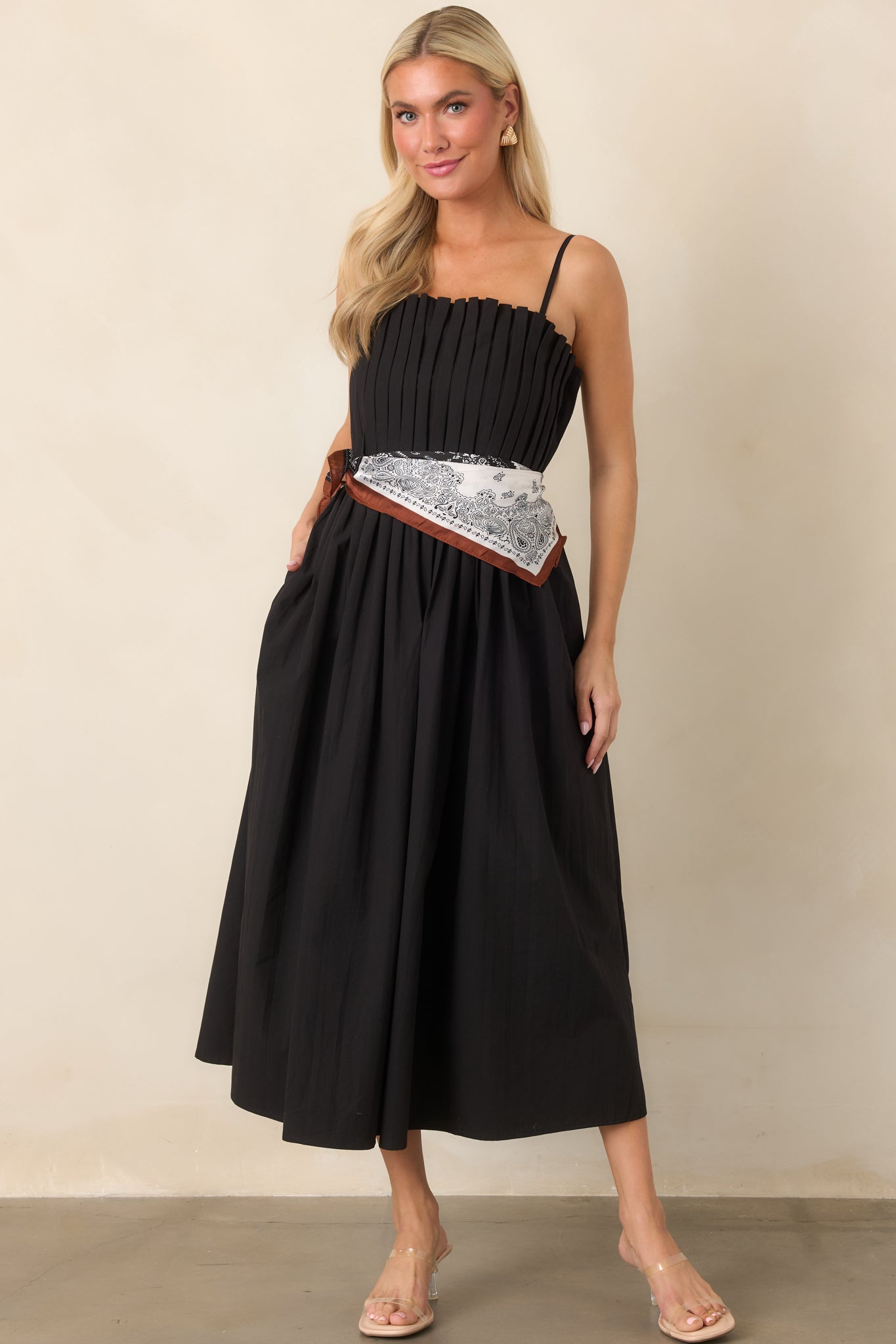 Classic black dress combining a softly fitted pleated bodice with a defined waist and graceful full midi-length skirt.
