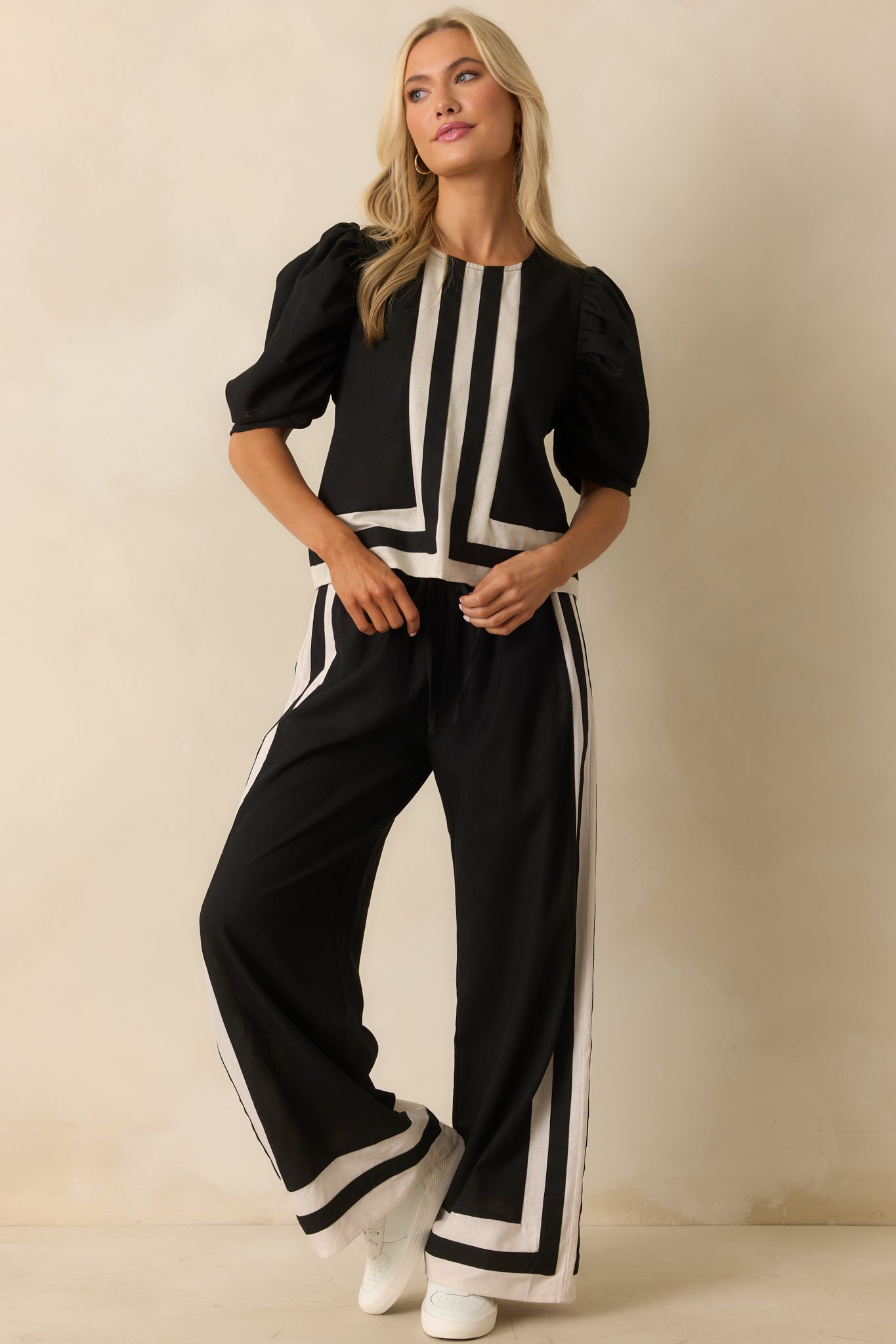 Black puff-sleeve top featuring an ivory-trimmed crew neck and defined center seam detail.