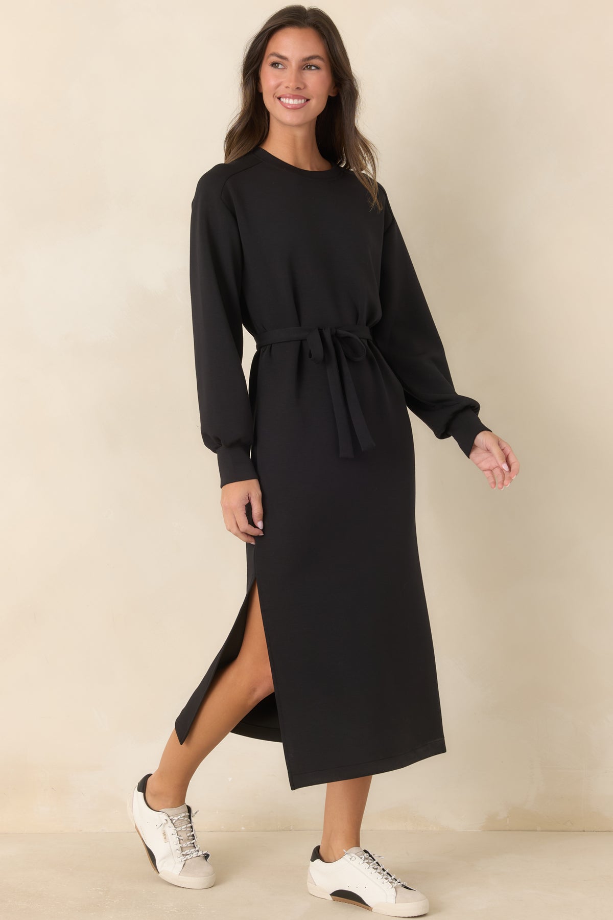 Relaxed black midi dress featuring long sleeves, banded cuffs, and a clean streamlined silhouette.
