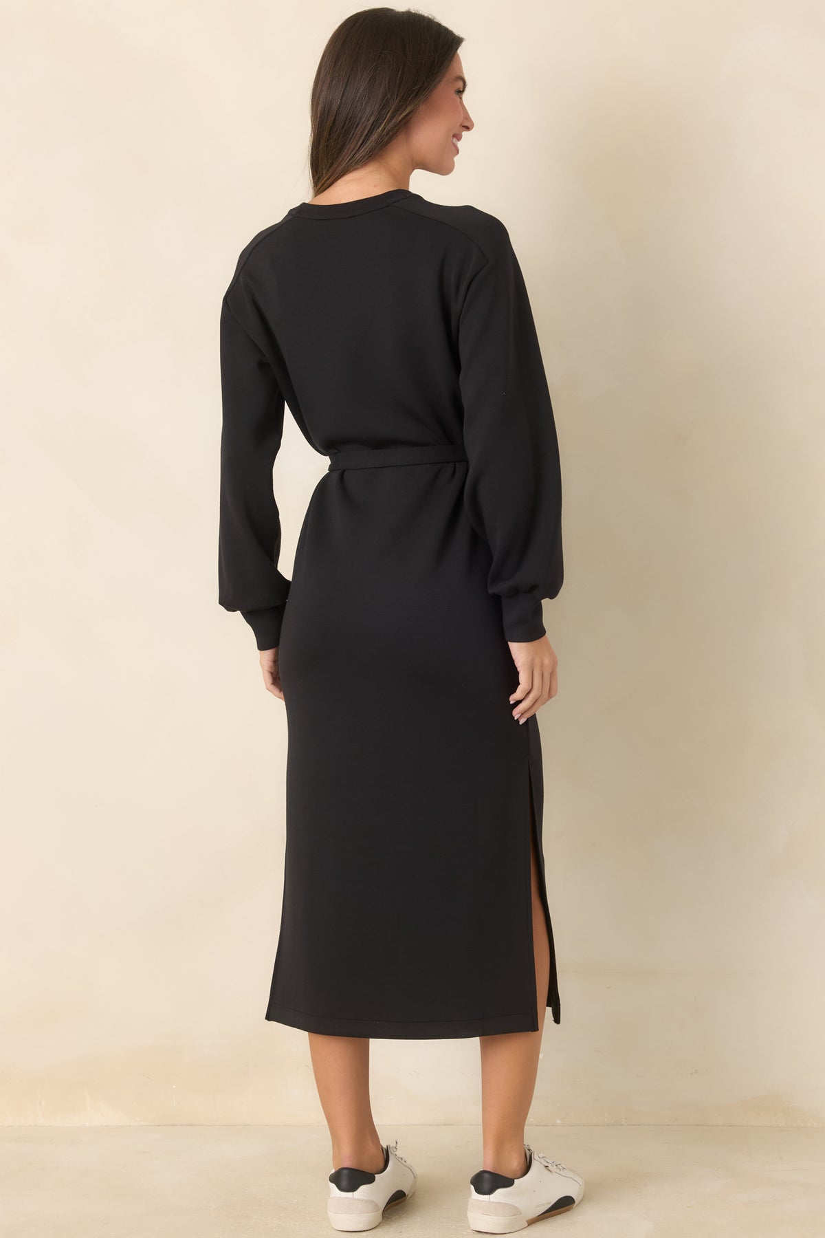 Rear of the black midi dress showing the relaxed silhouette, long sleeves, and matching waist tie.