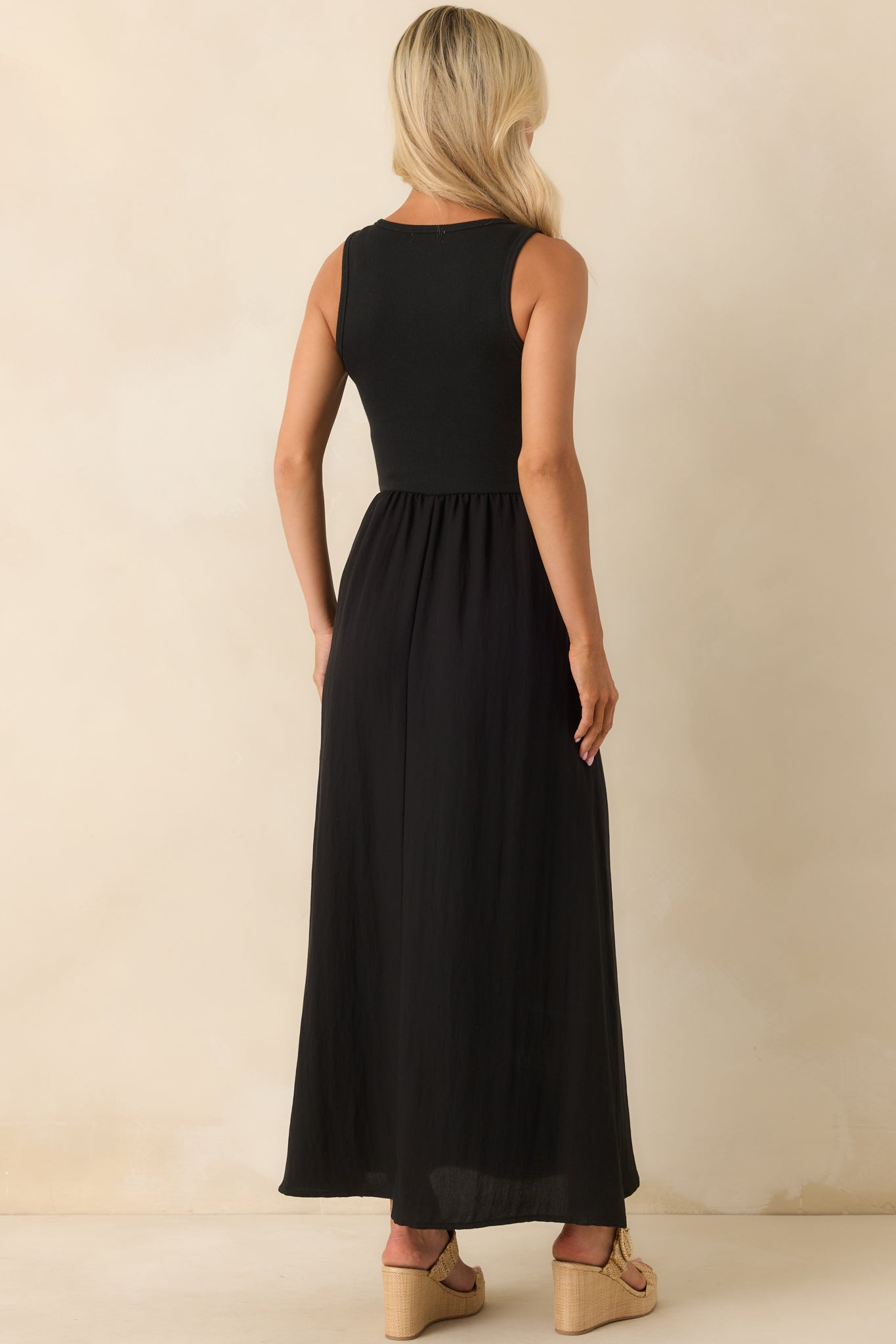 The back view of the black midi dress displaying the continuation of the ribbed bodice and the flow of the textured skirt.