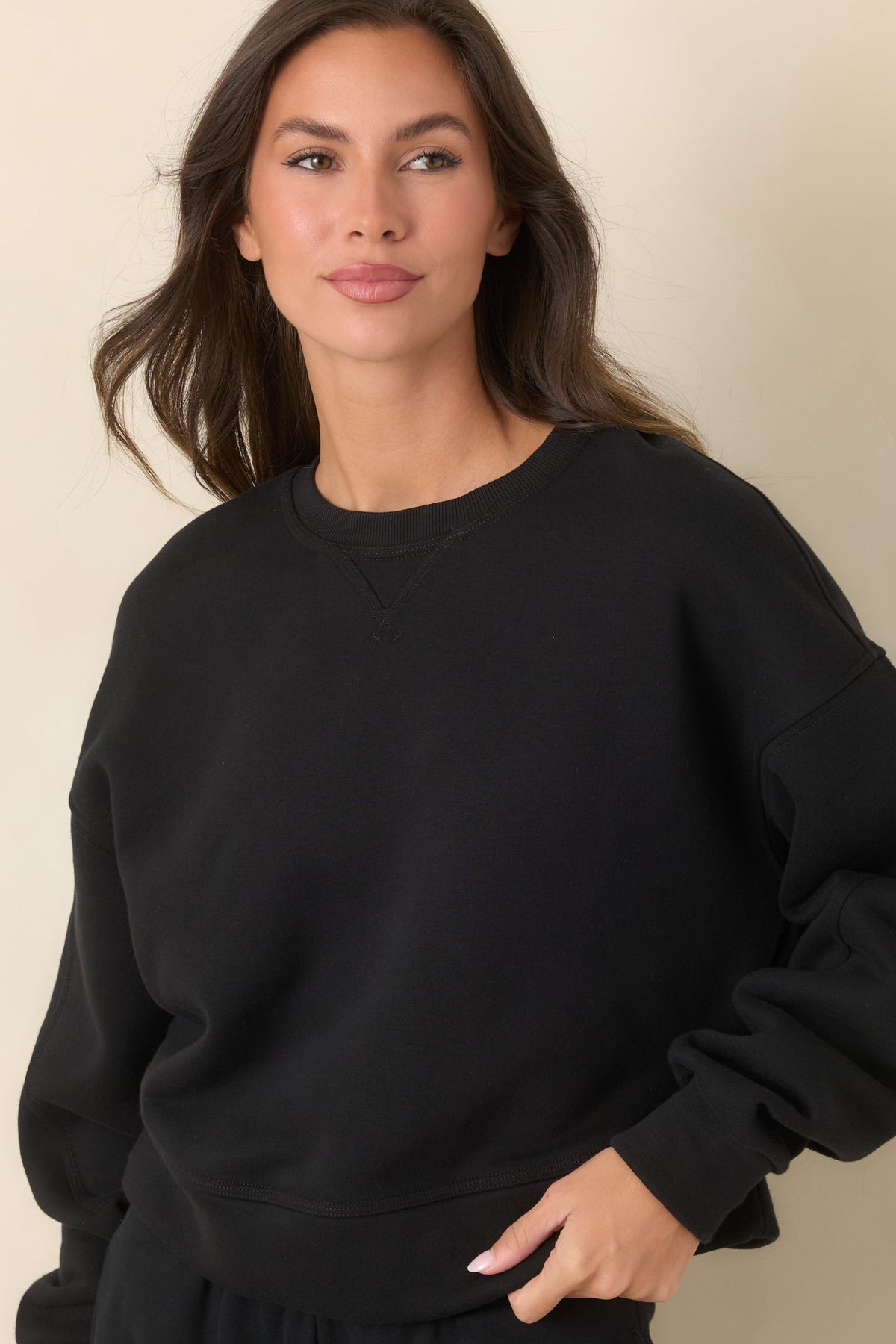 Black sweatshirt highlighting the ribbed crew neckline and stitched V-inset at the front.