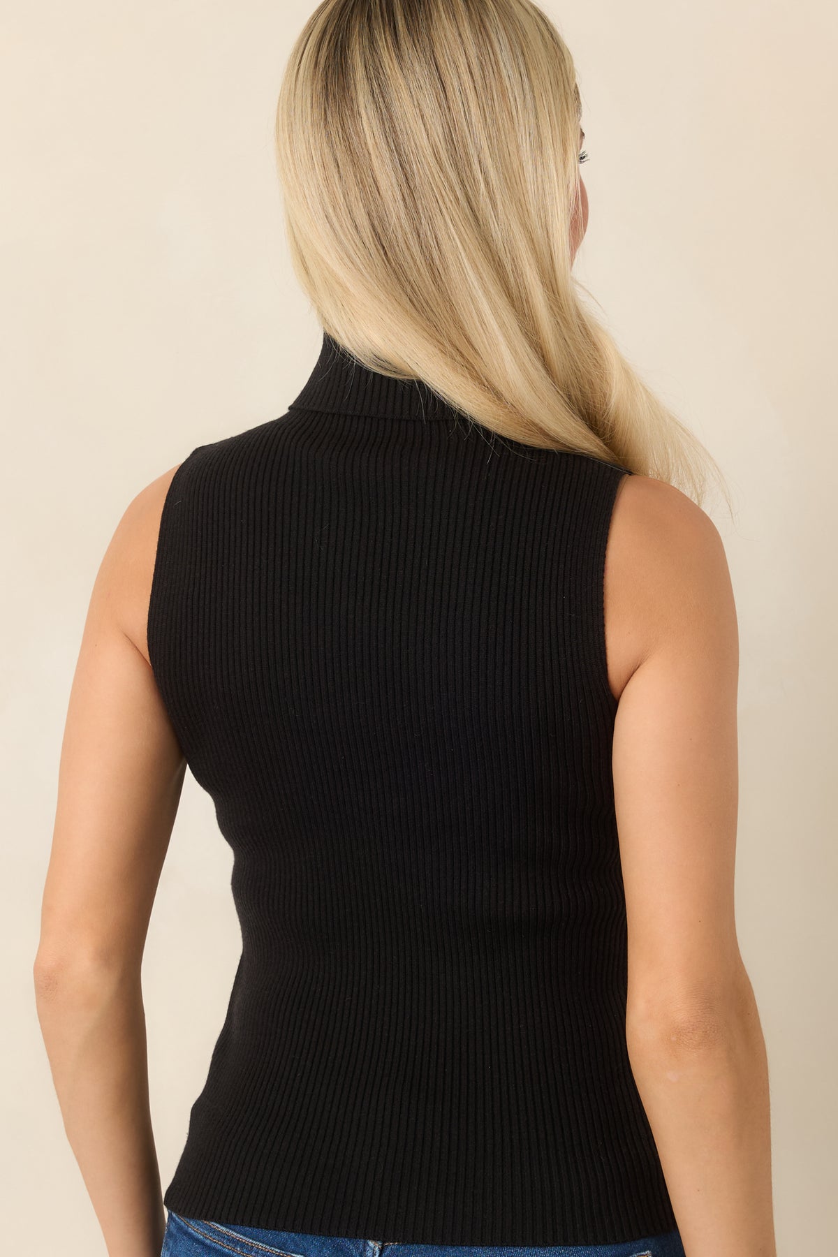Rear view of the rich black ribbed knit top with a fitted silhouette and clean hip-length hem.