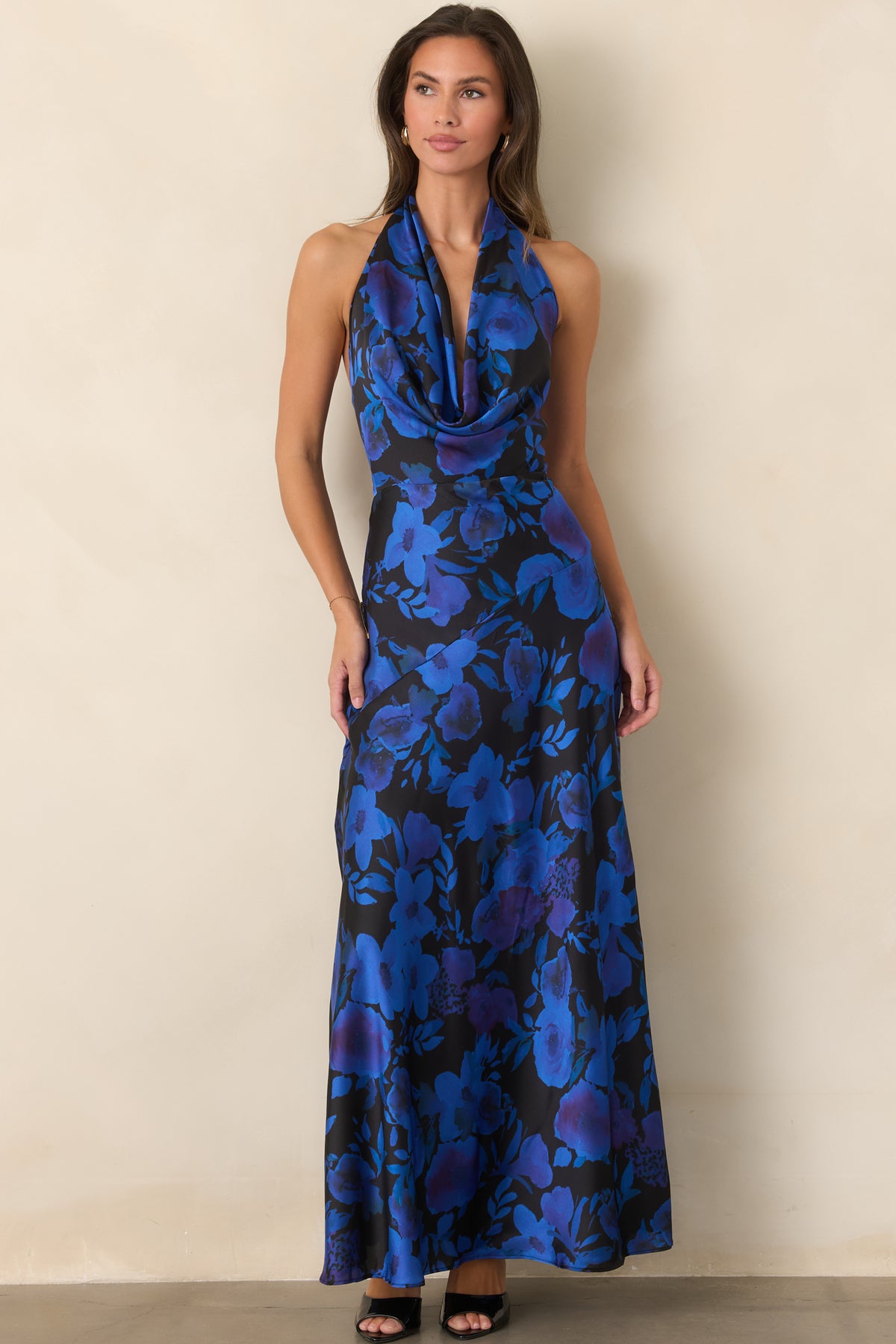 Black satin maxi dress with vivid cobalt and violet florals, a plunging draped cowl neckline, and flowing A-line skirt.