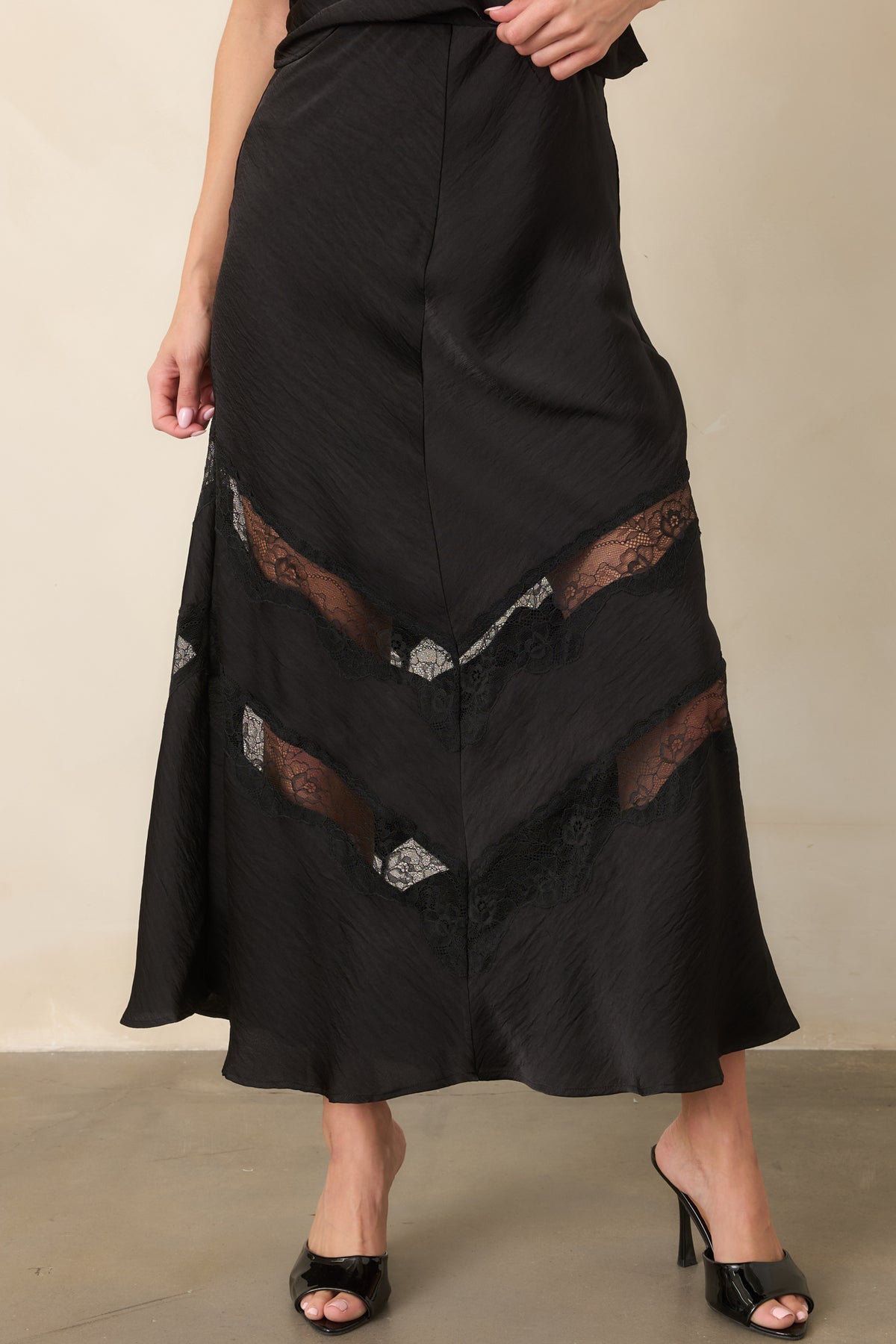 Black satin skirt highlighting its smooth fitted waist and softly crinkled finish.