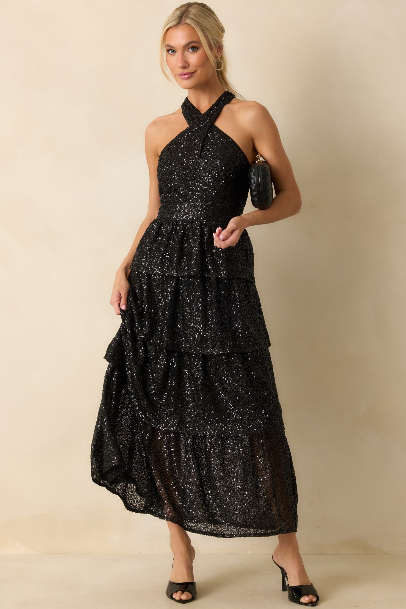 Halter-style black sequin maxi dress with a structured bodice and flowing tiered layers enhancing the shimmer.