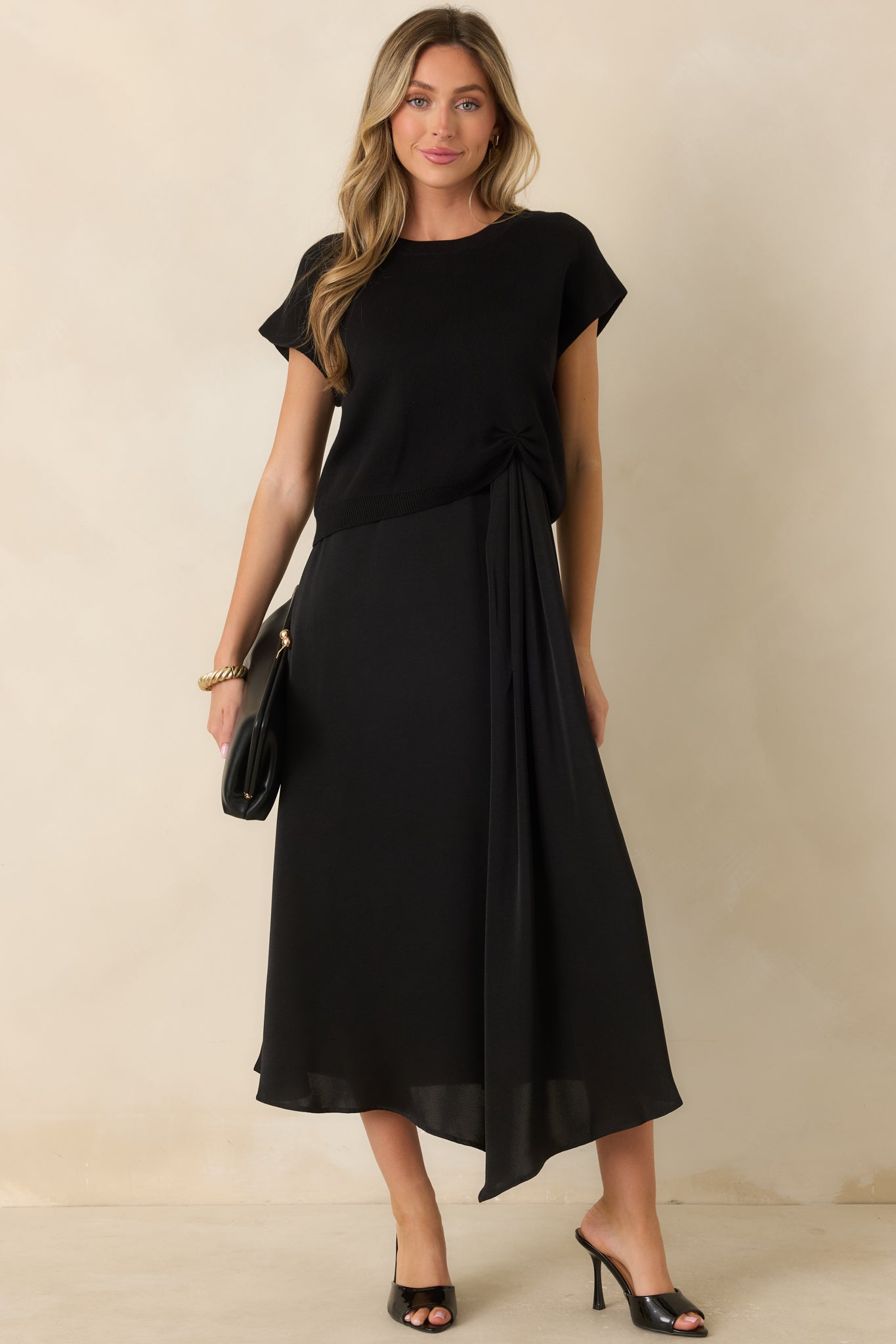 Soft black sweater featuring a timeless silhouette, cap sleeves, and gathered detailing along the front hemline.