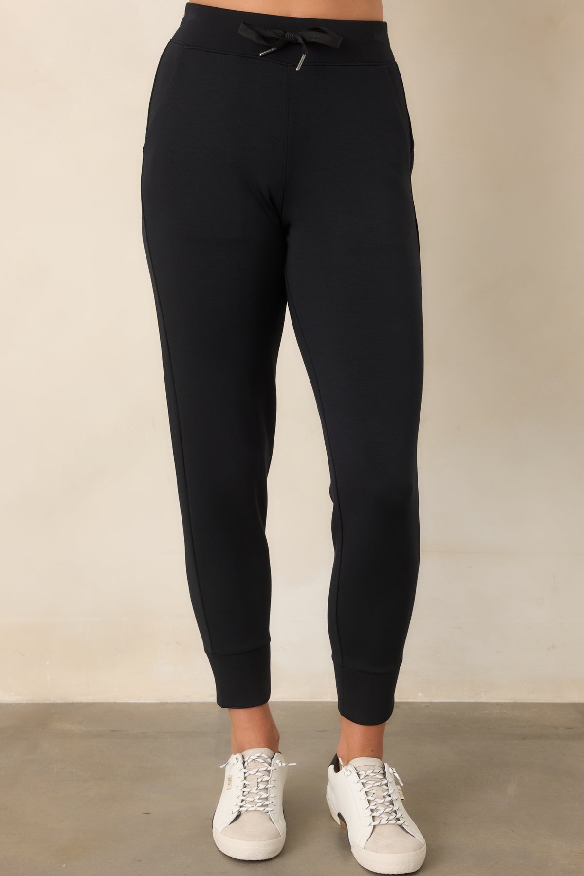 Black spacer joggers showing their smooth fabric, tapered leg shape, and clean banded cuff.