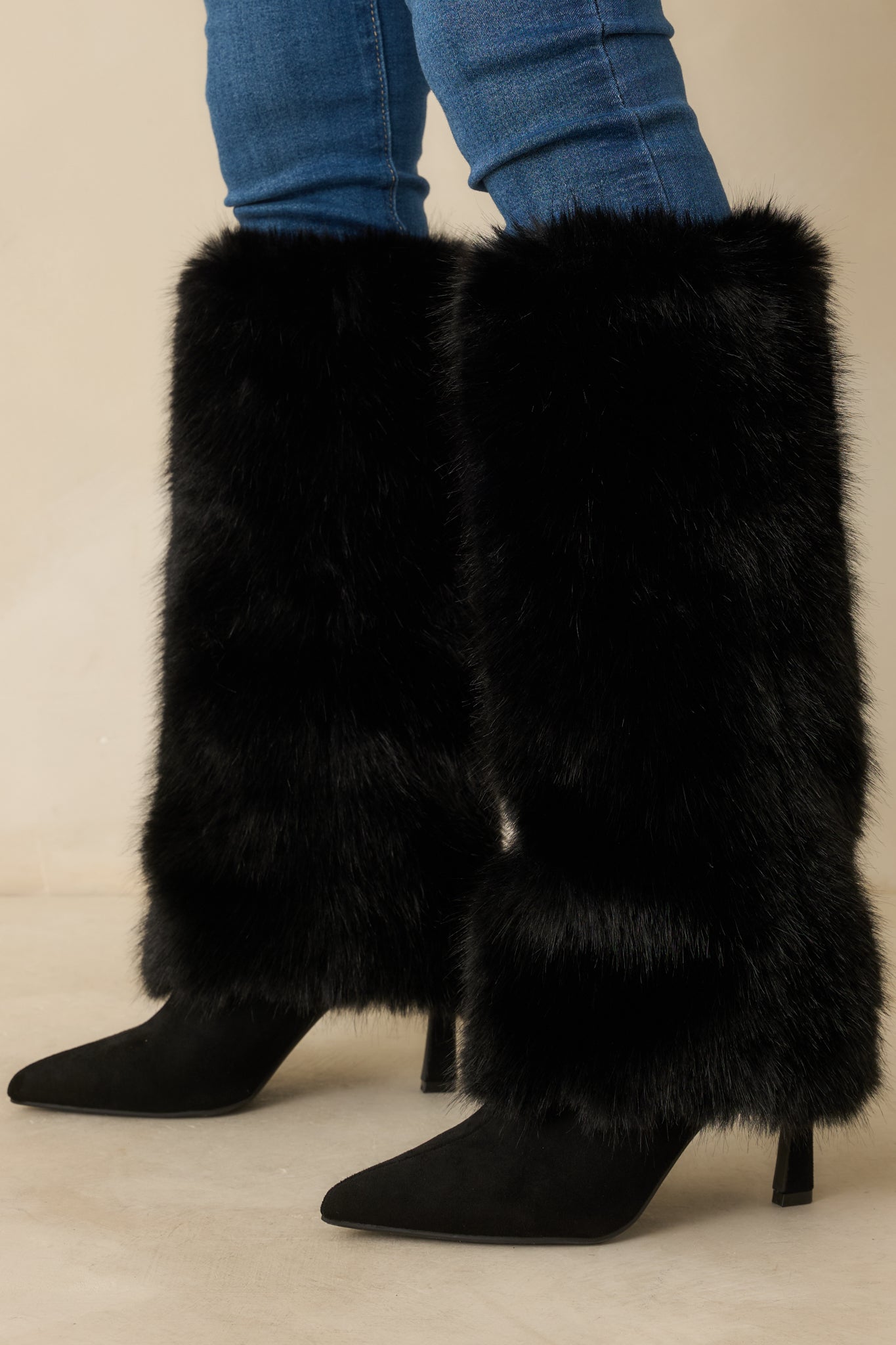 Cropped image highlighting the slim black stiletto heel and the transition from suede footbed to fur shaft.