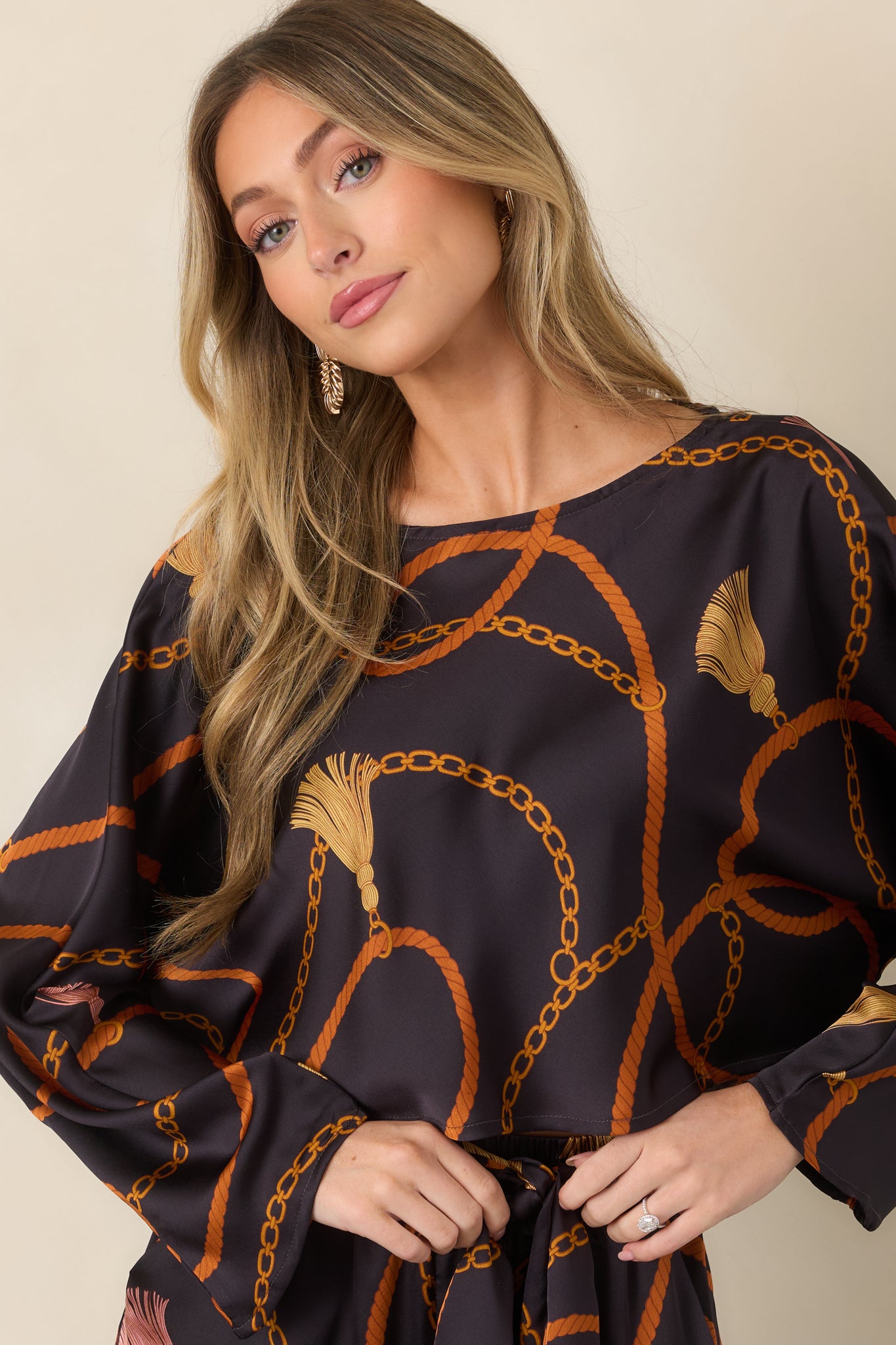 Black satin-feel top highlighting its relaxed cropped silhouette and intricate golden chain and rust rope pattern.