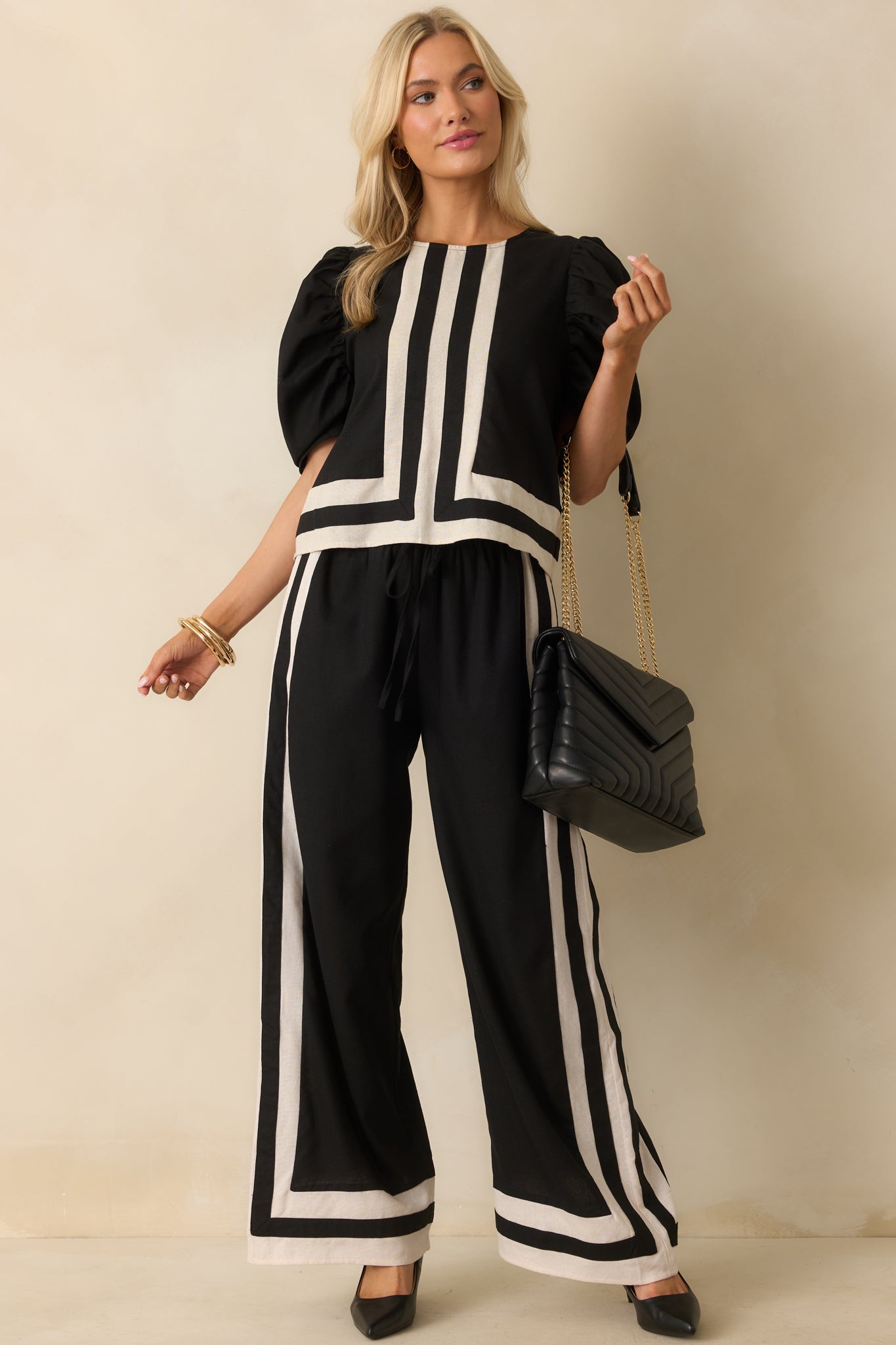 Elegant black top with ivory trim and puff sleeves, showcasing its relaxed silhouette and center seam detail.