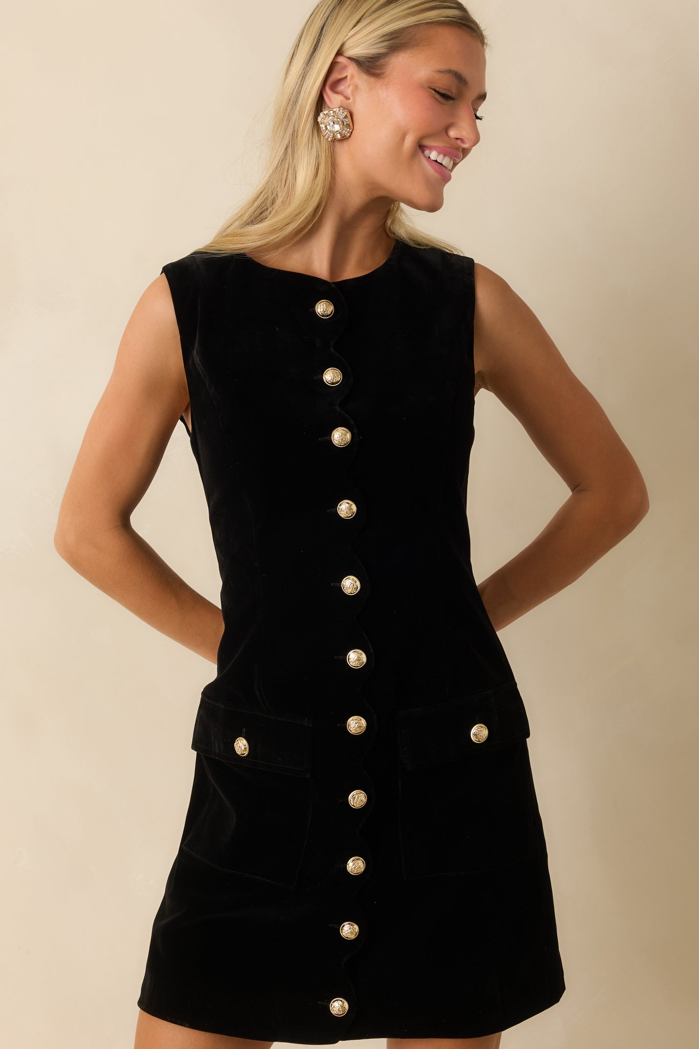Black velvet dress highlighting the elegant scalloped trim and gold button accents.