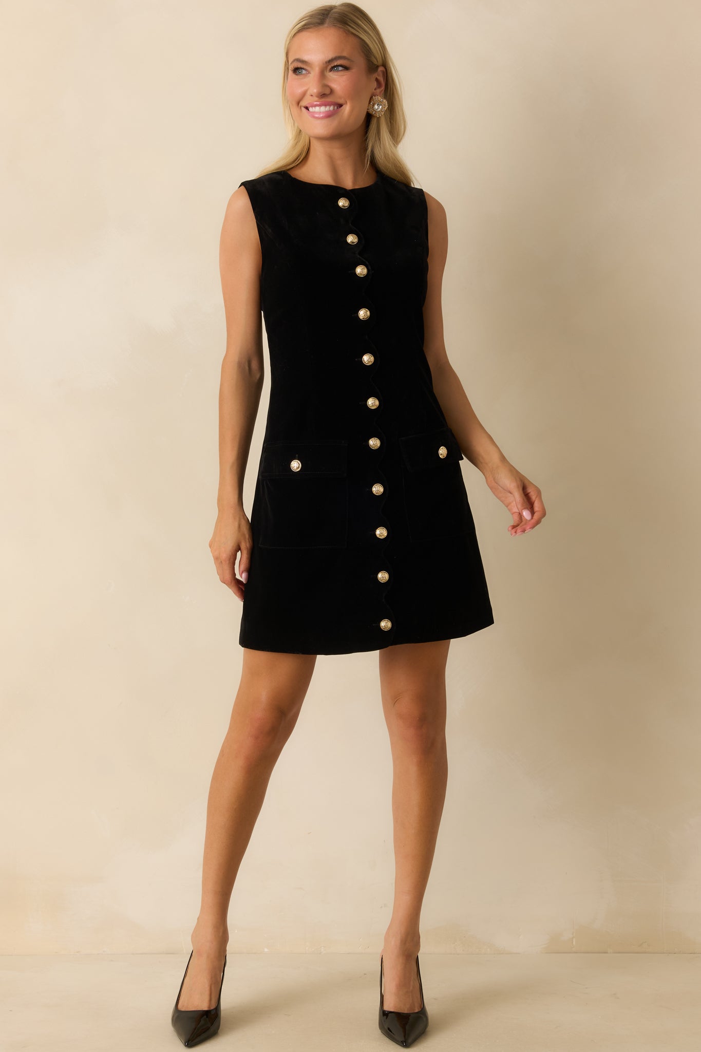 Sleek black velvet mini dress showing its structured shape and refined button-front detailing.