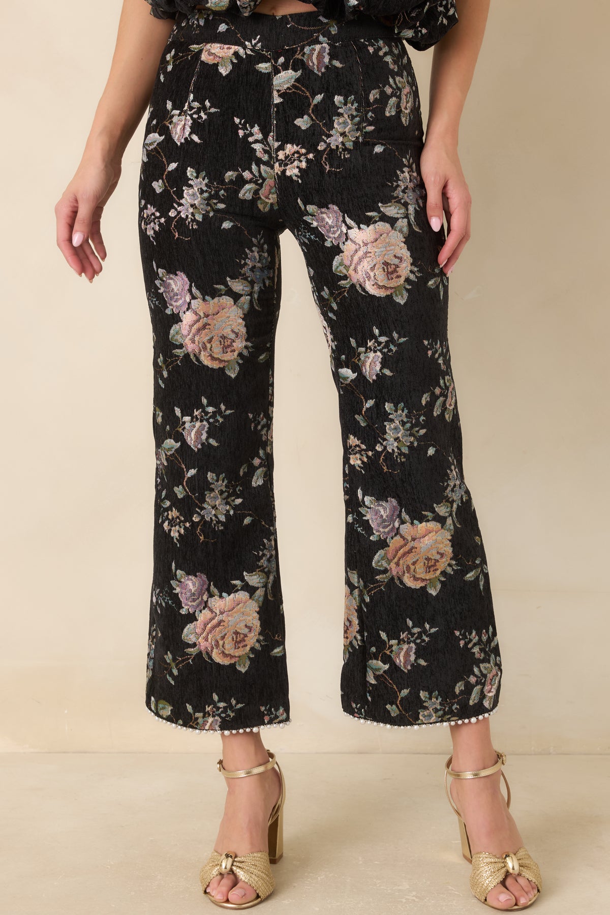 Vintage-inspired floral cropped pants featuring a defined waistband and textured black fabric.