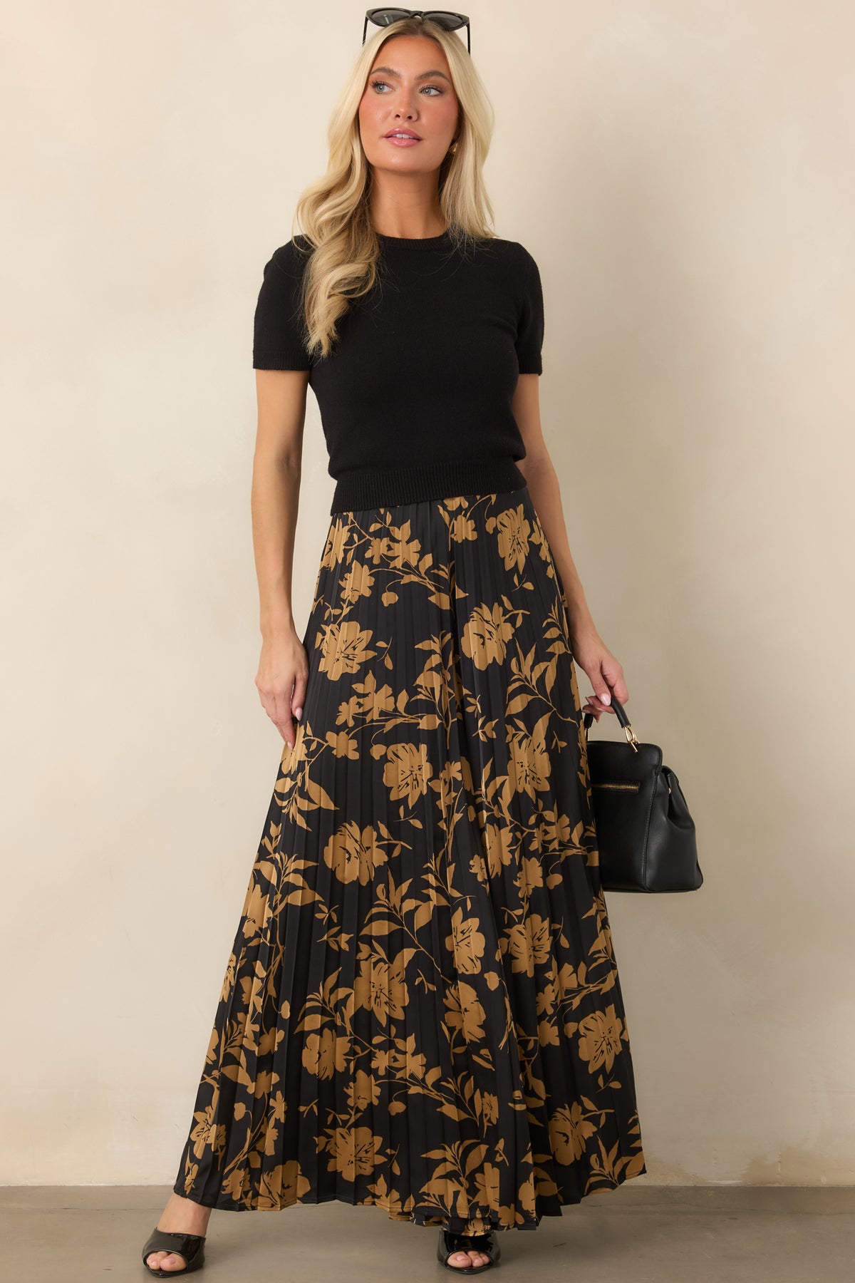 Flowing black wide-leg pants showcasing golden floral motifs and dimensional accordion pleating throughout.