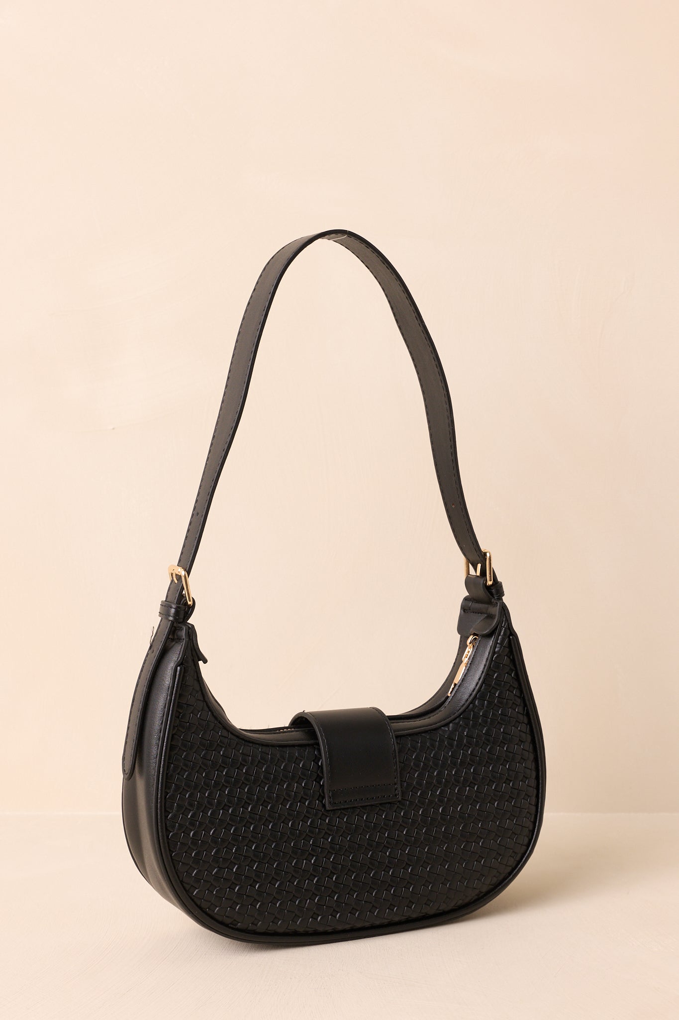 Rear view of black shoulder bag with smooth panel and flat adjustable strap.