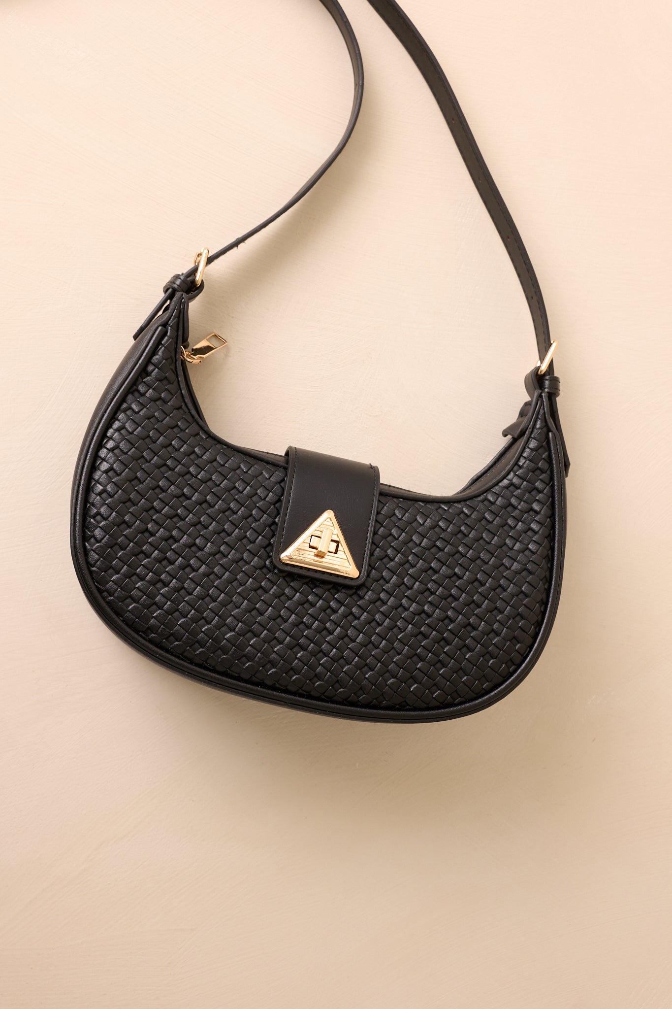 Black shoulder bag highlighting structured base and gold zipper closure.