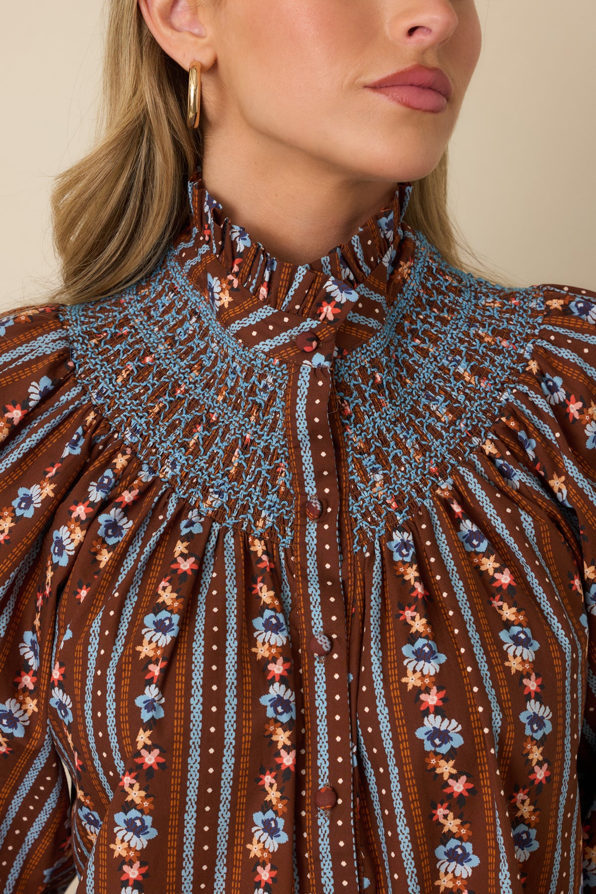 Close-up detail of the blouse showing petite blue and orange florals, contrasting blue smocking, and fabric-covered buttons.