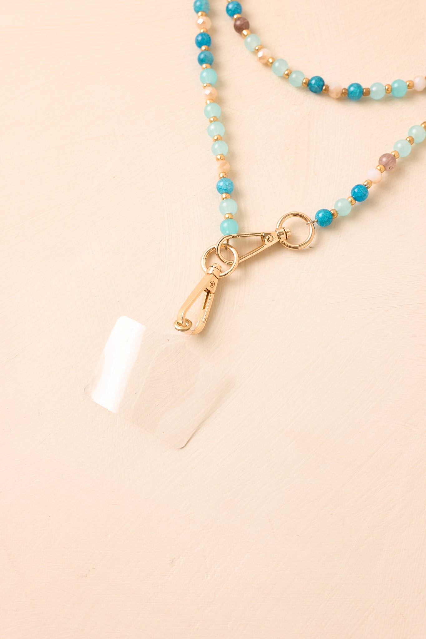 Detailed view of the blue beaded phone lanyard, highlighting the smooth bead textures, coordinating colors, and gold spacer beads.