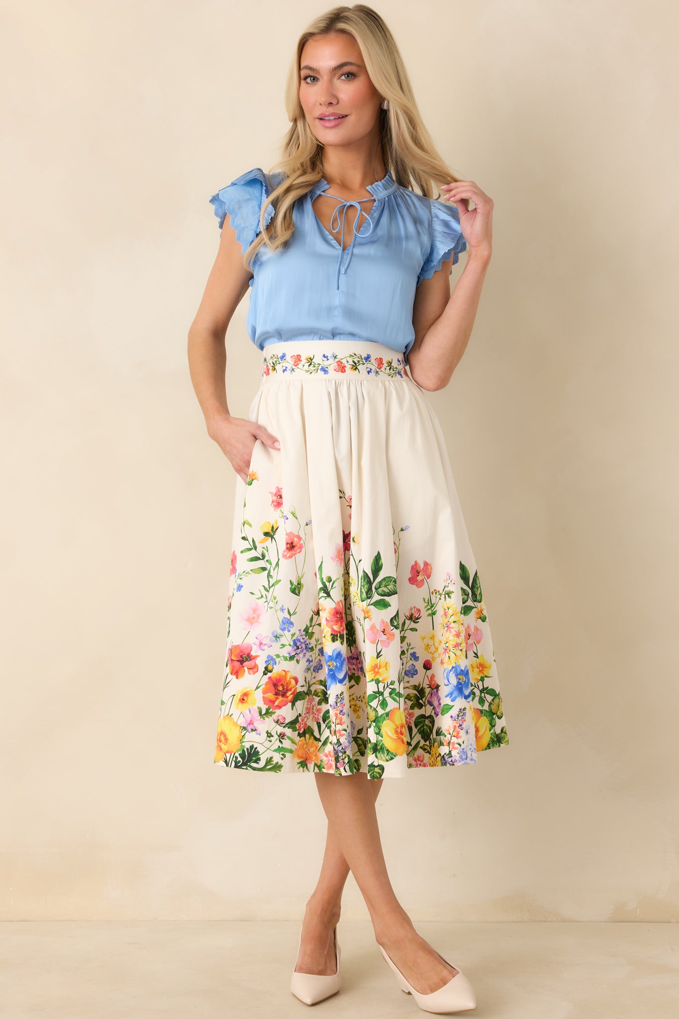 Front view of a blue blouse featuring adjustable tie detail at the neckline and airy drape through the body.